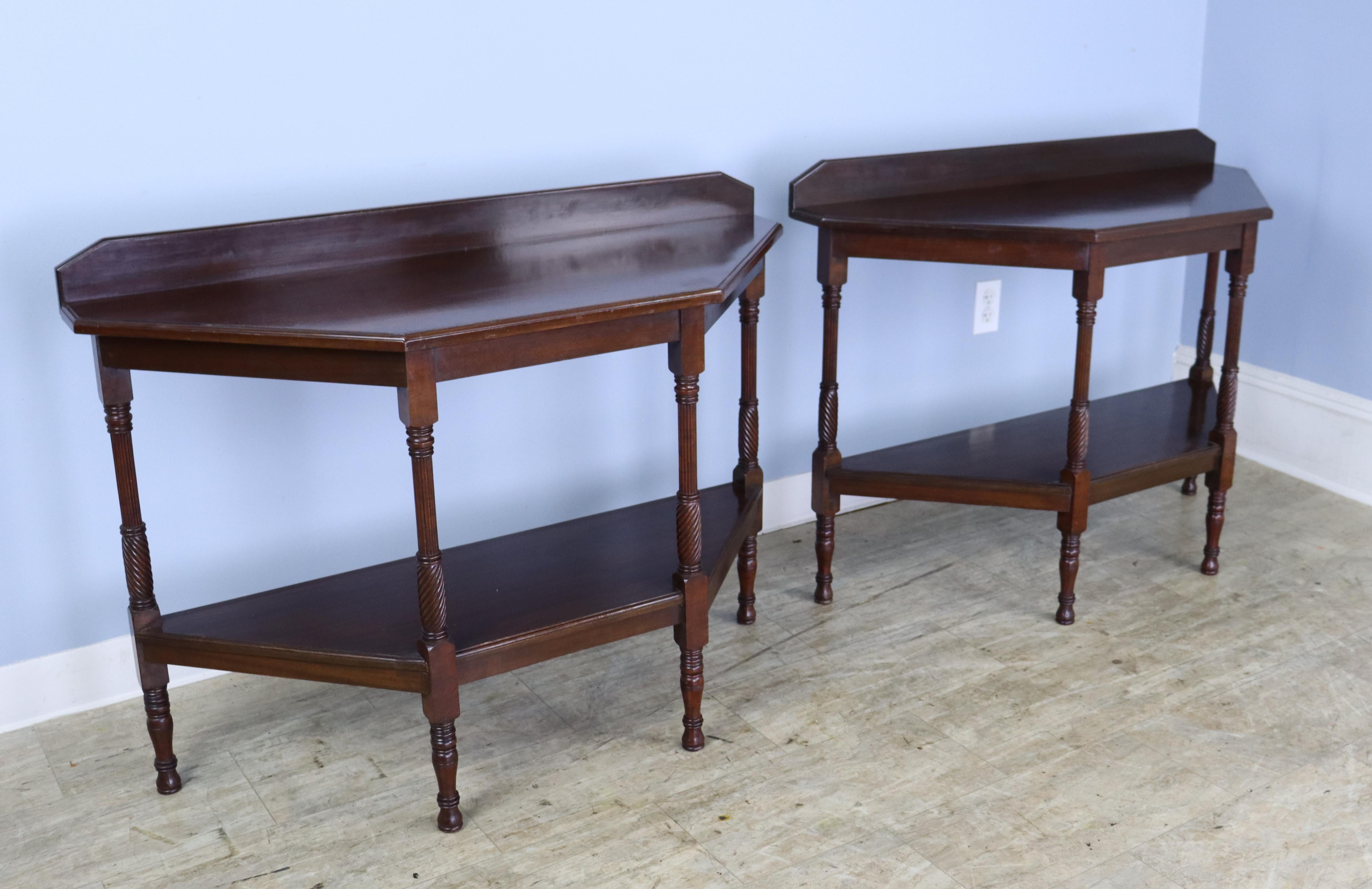 An elegant pair of geometric mahogany consoles with turned legs. Would be right on either side of an entryway or window. Well made and sturdy. Although they are identical, the galleried back prevents the two tables from marrying well into a single