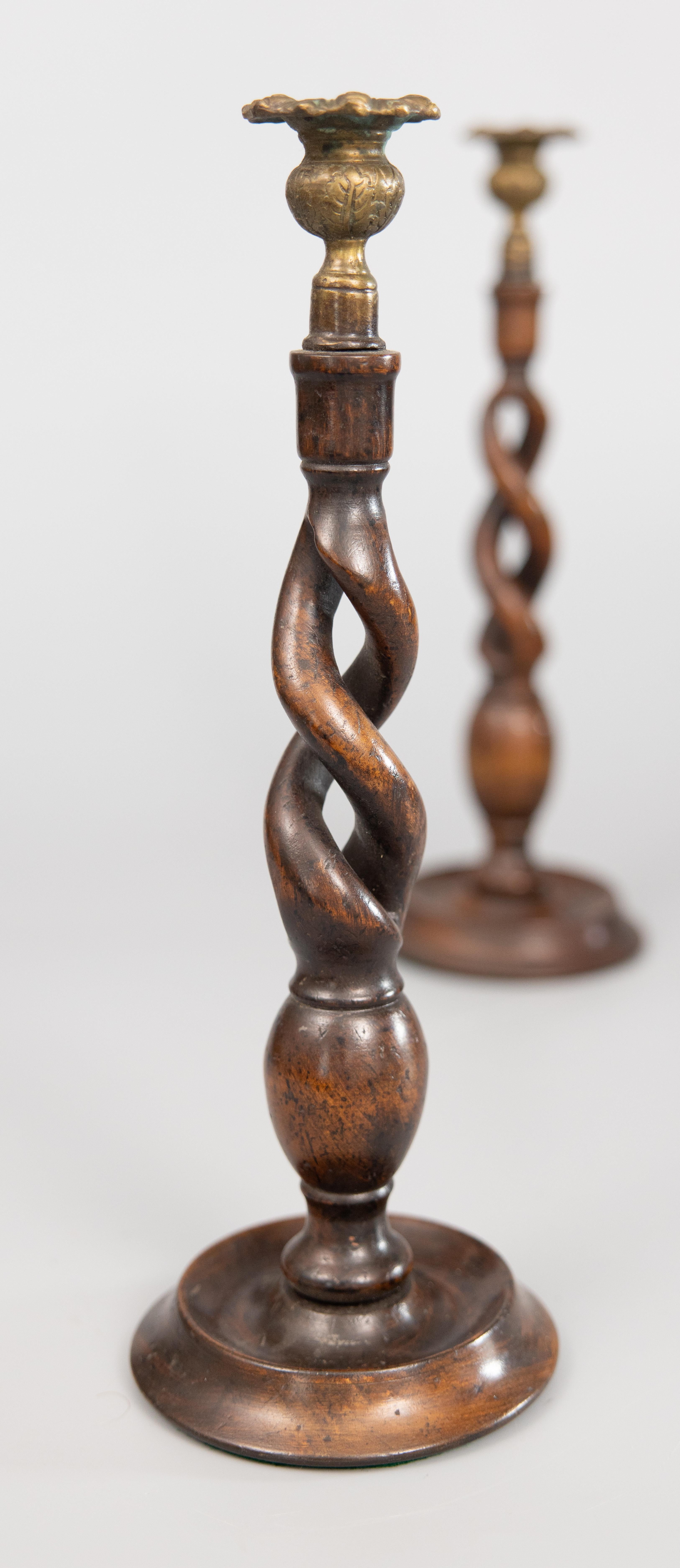 A fine tall pair of English barley twist oak and brass candle holders, circa 1900. This gorgeous pair have hand cast brass thistle top candle cups and hand carved open barley twist stems on hand-turned bases. They would make a stunning addition to a