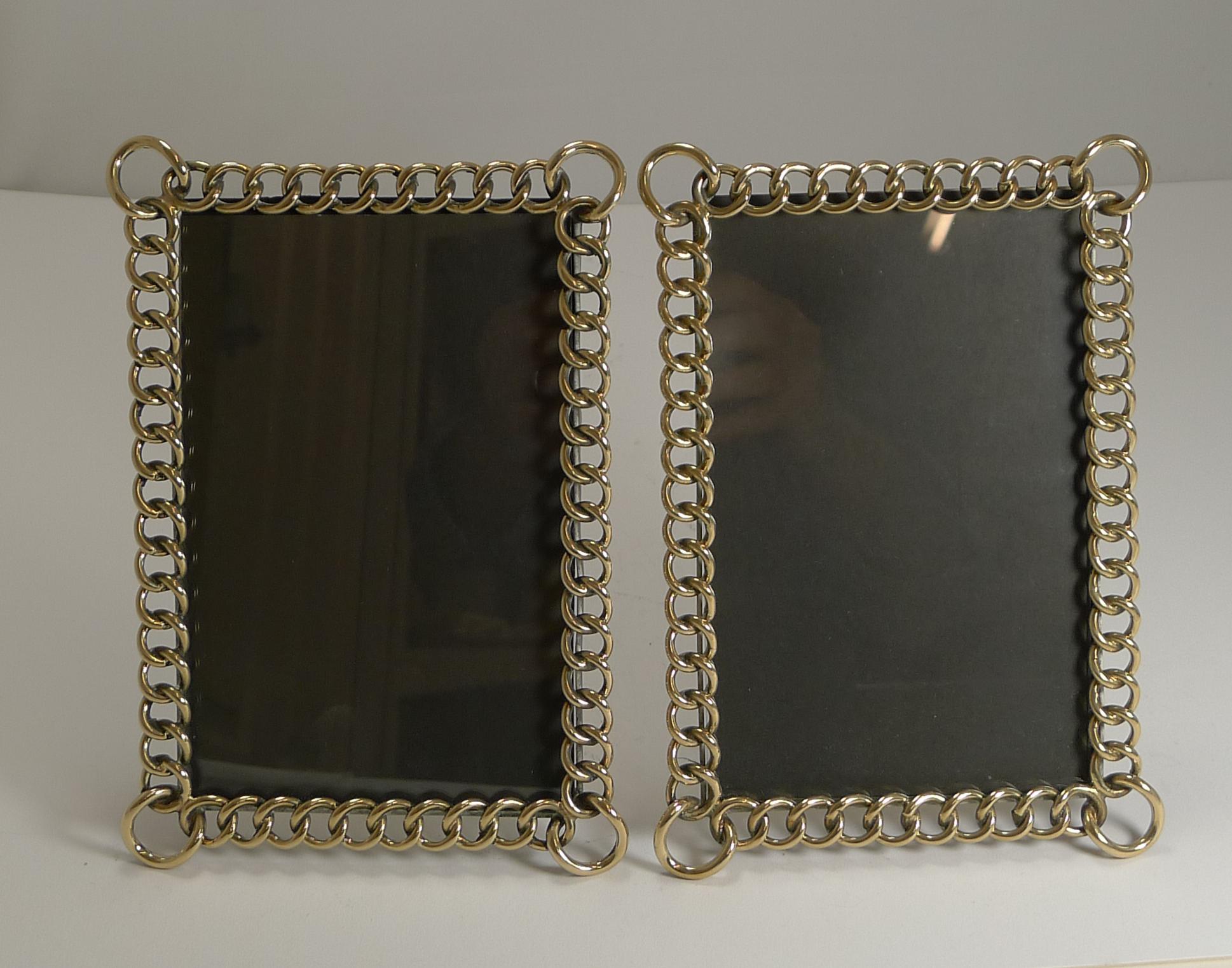 A handsome pair of late Victorian English photograph frames made from interlocking solid brass rings and standing on the original folding easel stands.

Victorian in Era dating to circa 1890. Each measuring 8