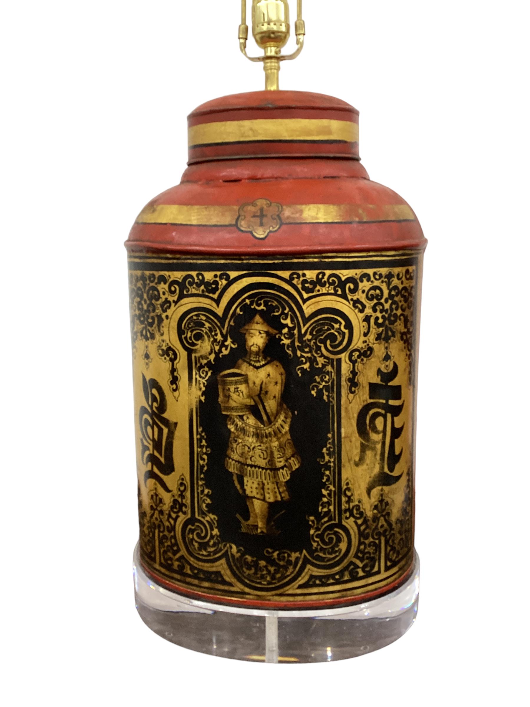 A pair of large oval English tole tea canisters with hand painted and stenciled decoration on a red ground with gilt reserve, the center panel having a Chinese figure on a gilt ground with Chinese calligraphy in black ink now mounted as lamps on