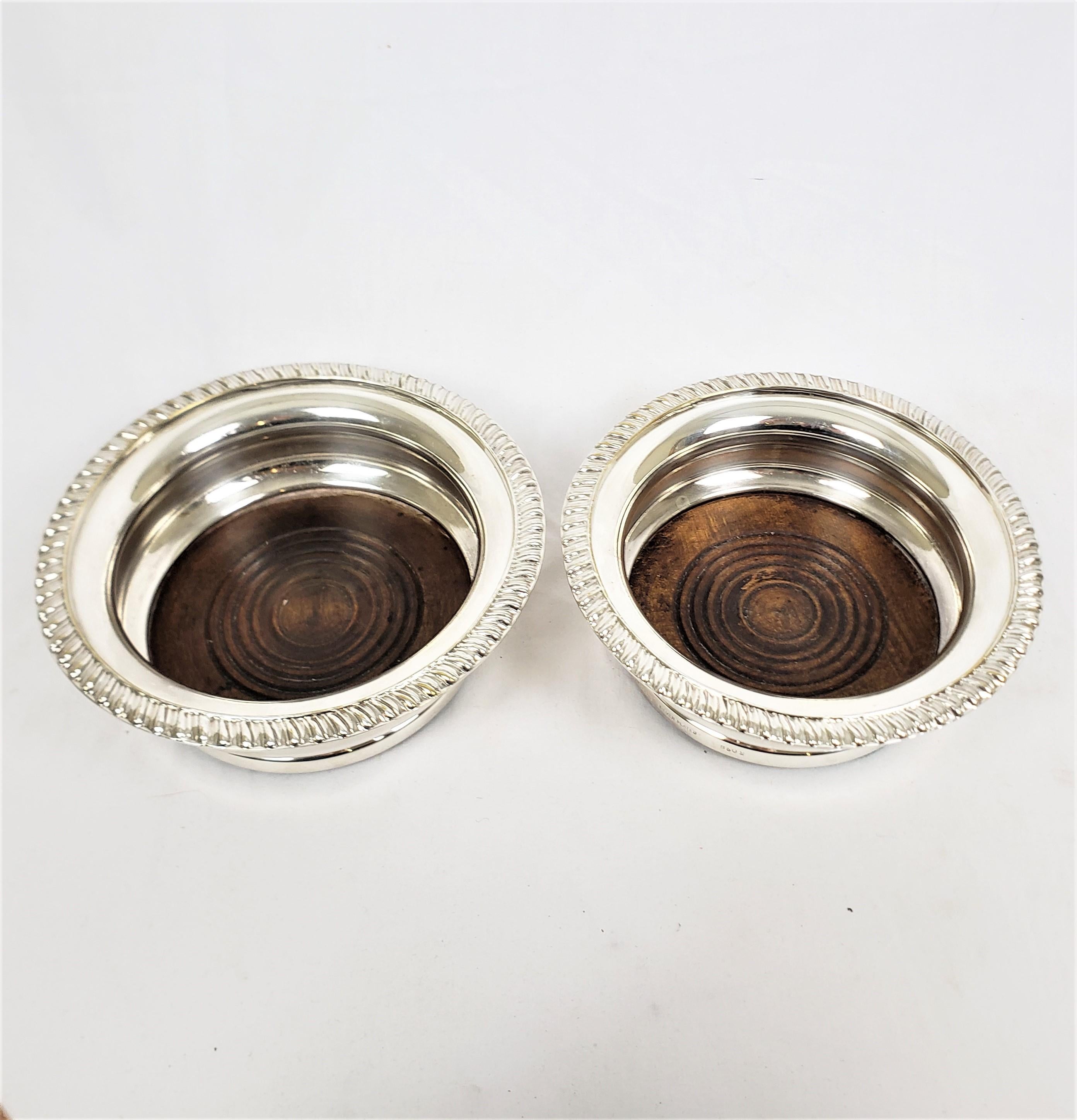 This pair of large wine bottle coasters are unsigned with respect to the maker, but originate from England and date to approximately 1920and done in a period Art Deco style. The bottle coasters are composed of silver plate with deep ribbed sides and