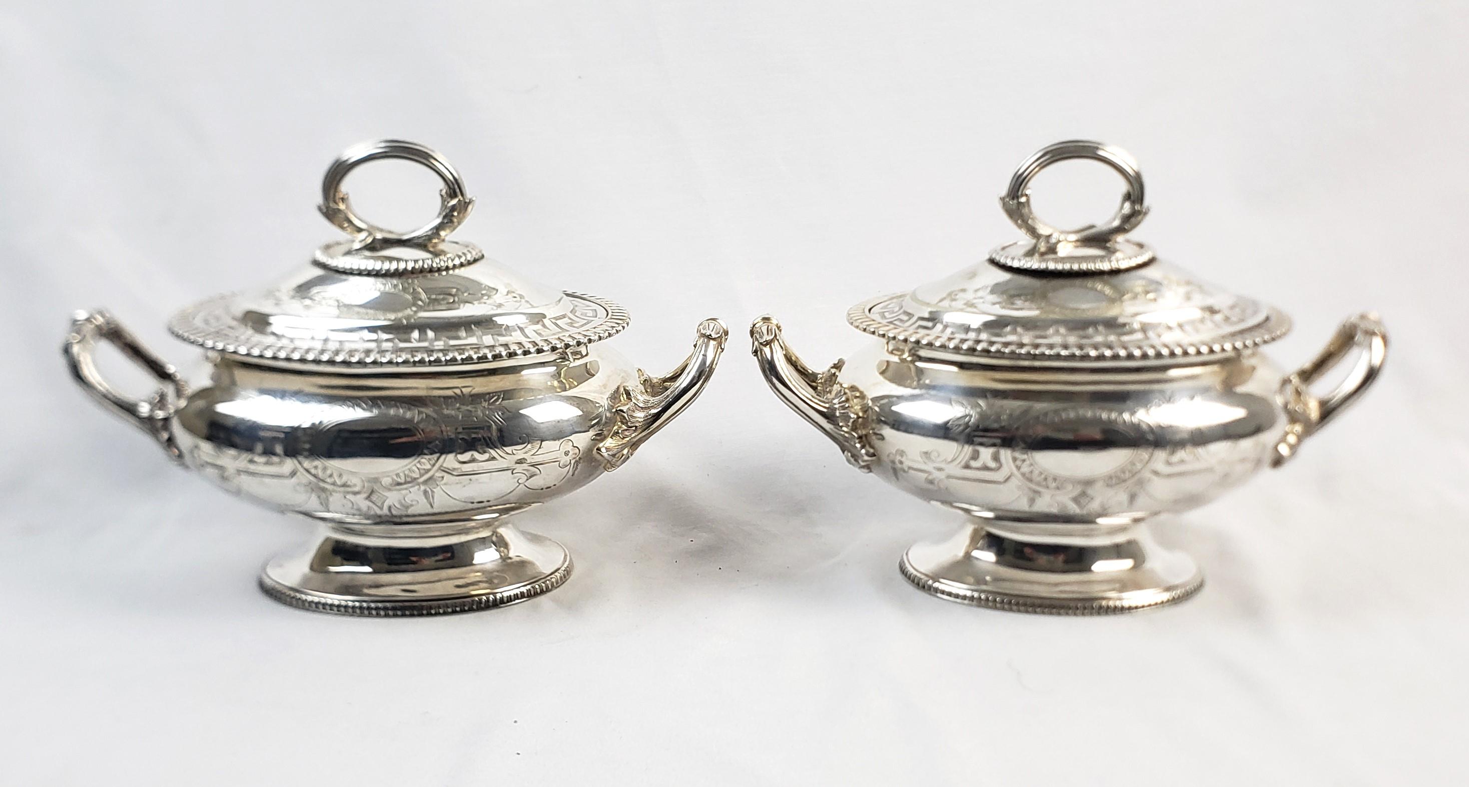 This pair of antique covered sauce tureens were made by the Thomas Bradbury and Sons of England and date to approximately 1900 and done in the period Edwardian style. The tureens are composed of silver plate and are ornately engraved with a Greek