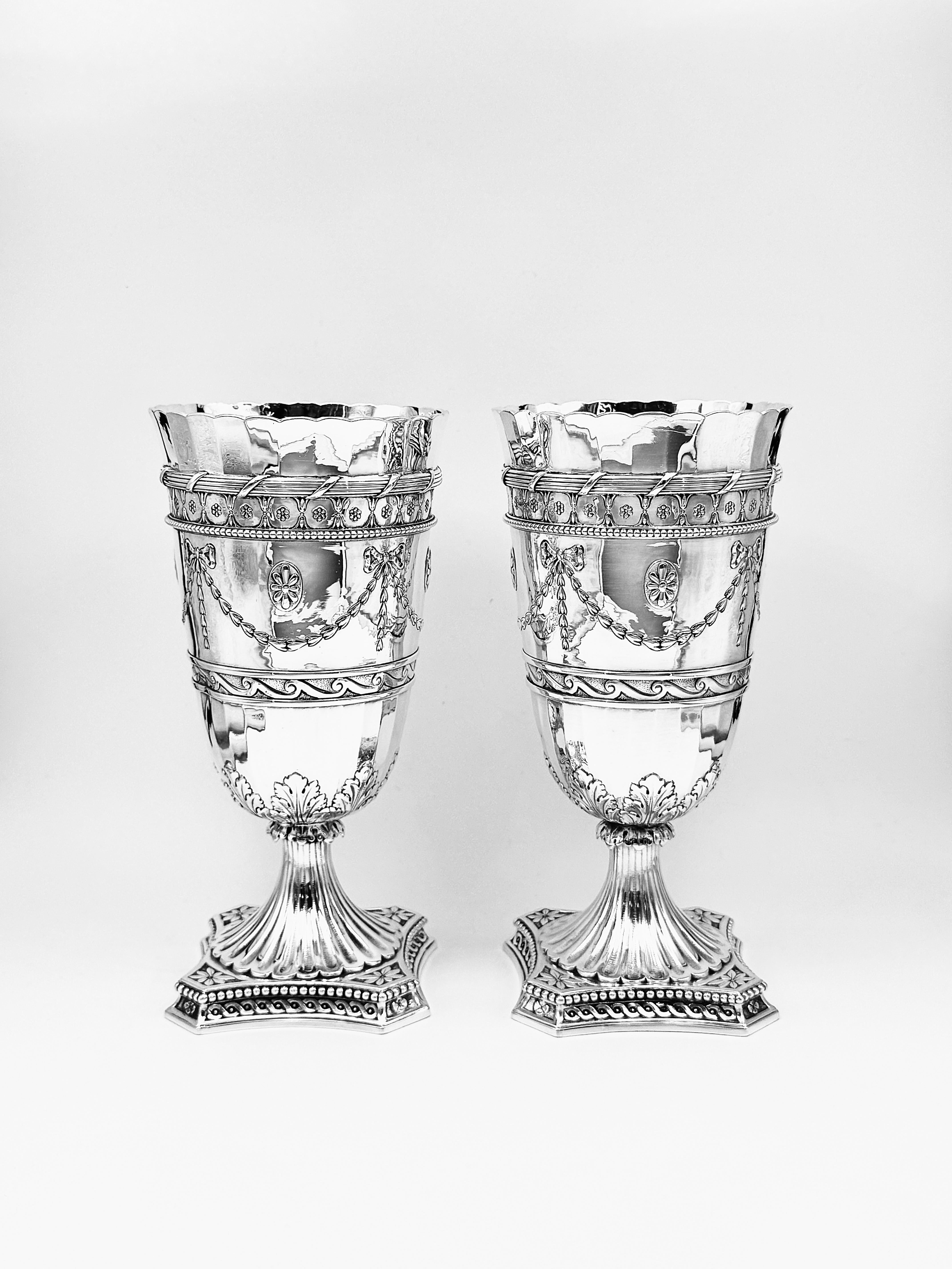 Ein Paar viktorianische Silbervasen von Elkington & Co, Birmingham, 1898. Jede Vase ist mit applizierten Blumen, Schleifen und Blütenblättern verziert und steht auf einem geformten quadratischen Sockel, der mit Akanthusblättern, geometrischen