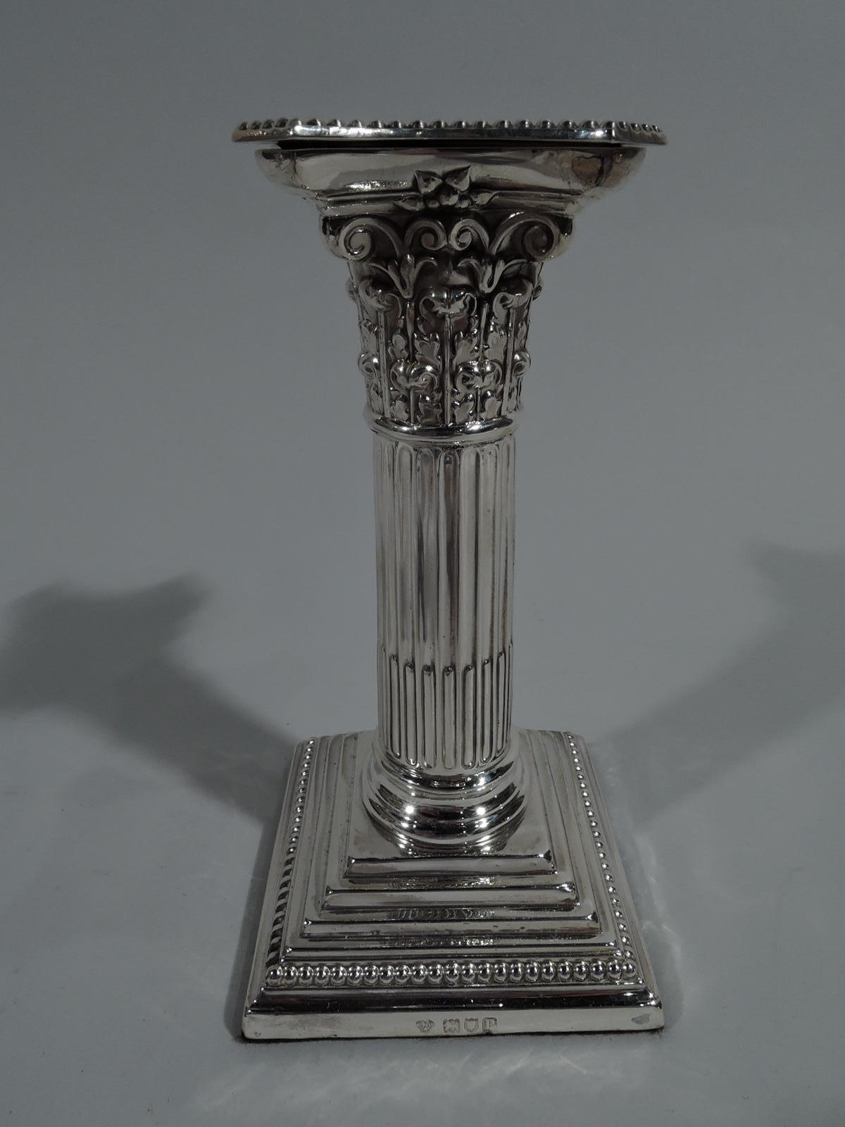 Pair of George V sterling silver candlesticks. Made by William Hutton & Sons, Ltd in London in 1910. Each classical column with stop-fluting, stepped and beaded square vase, and Corinthian capital. Bobéches concave and beaded. Underside felt lined.