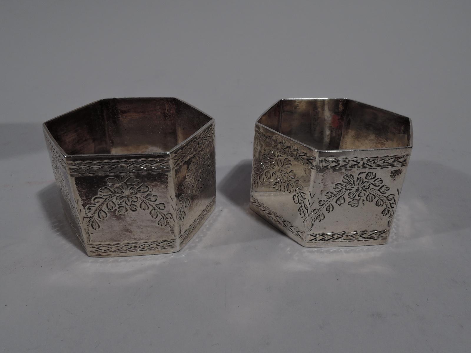 Pair of Victorian sterling silver napkin rings. Made by Martin, Hall in Sheffield in 1888-1890. Each: hexagon engraved with garlands and leafy borders. Traditional ornament applied to modern form. In leather-bound case with silk lining and fitted