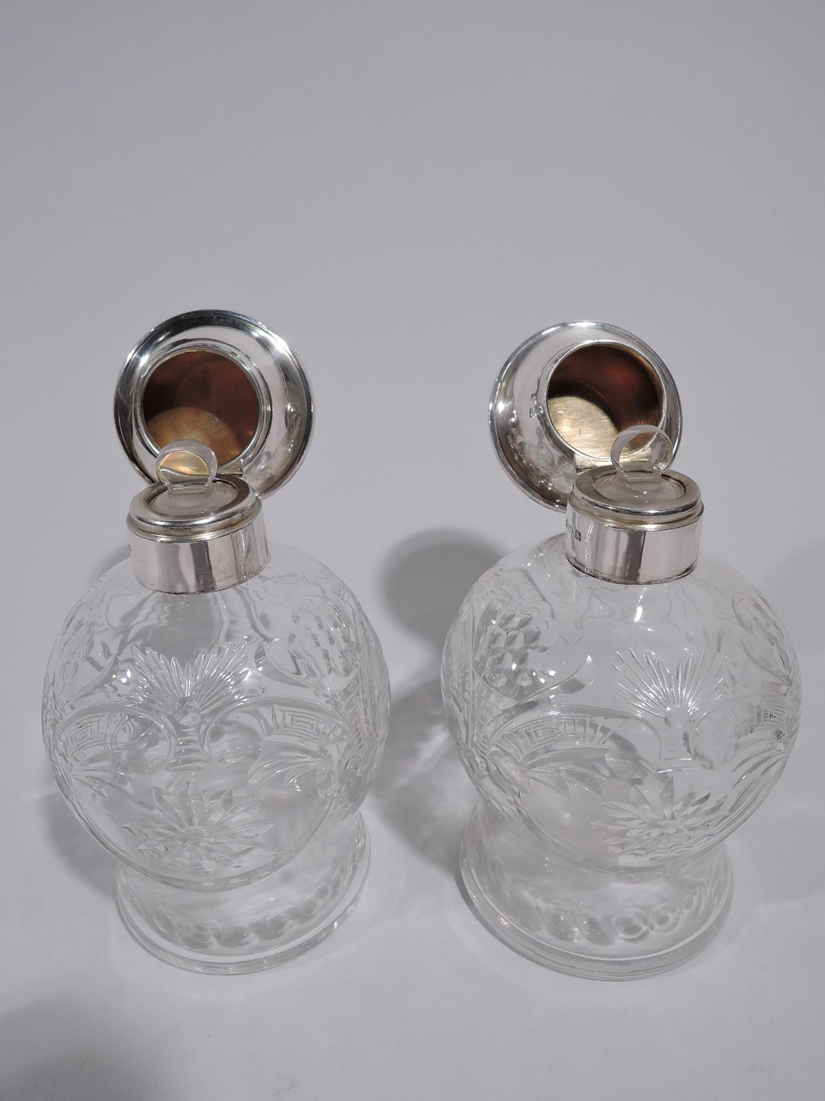 Pair of George V perfumes. Made by Adie Bros in Birmingham in 1925. Each: Crystal baluster bowl with scrolls, flowers, swags, and paterae. Short neck with sterling silver collar and hinged truncated-cone cover. Cover top flat with engine-turned wave