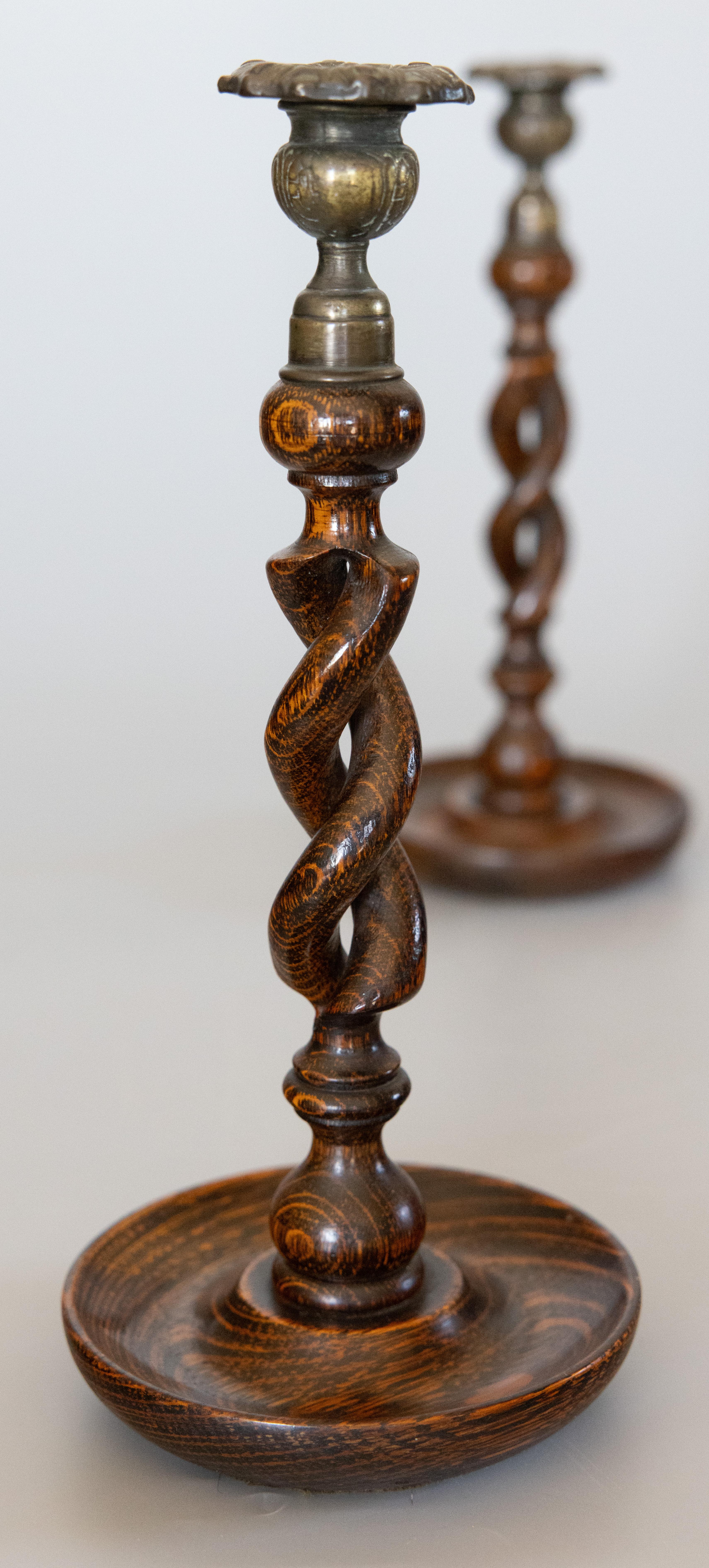 A fine tall pair of English barley twist tiger oak and brass candle holders, circa 1900. This gorgeous pair have hand cast brass thistle top candle cups and hand carved open barley twist stems on hand-turned bases with a richly figured grain and