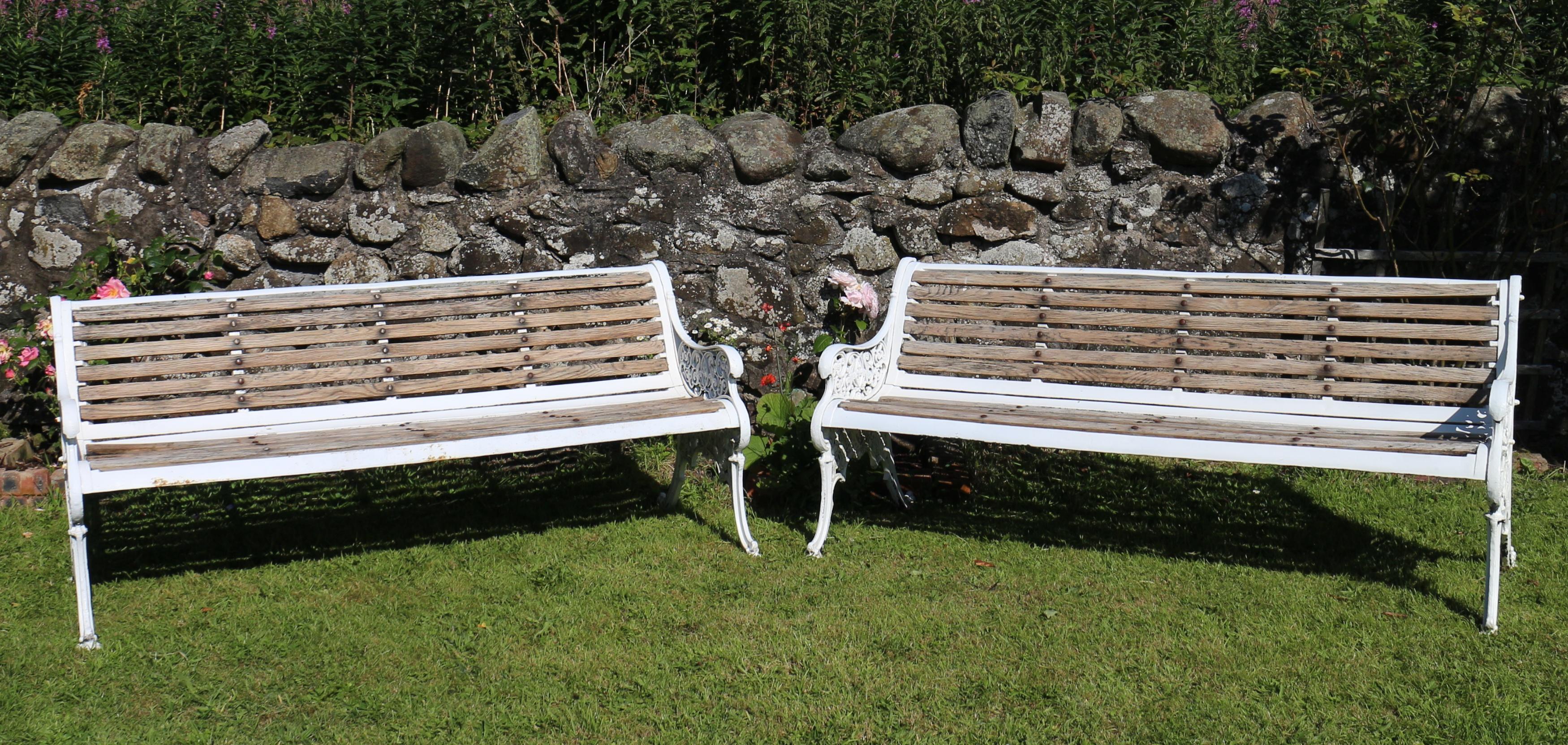 A pair of Victorian cast iron garden seats dating to circa 1870. The ornate pierced ends with scrolling foliage and outsplayed legs on scroll feet and with diamond registration marks. With oak slats set into a cast iron ergonomically shaped seat and