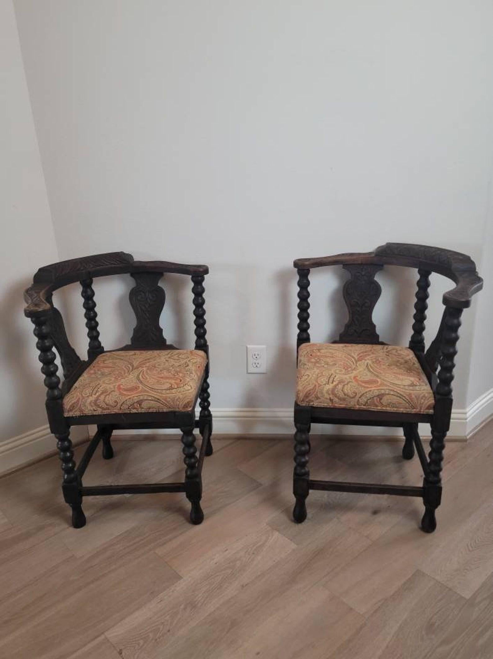 A pair of antique European carved oak corner chairs with beautifully aged dark rich patina. 

Born in the early/mid-19th century, hand-crafted in Moorish Renaissance taste, having heavily carved shaped crest rail over vasiform splats with floral