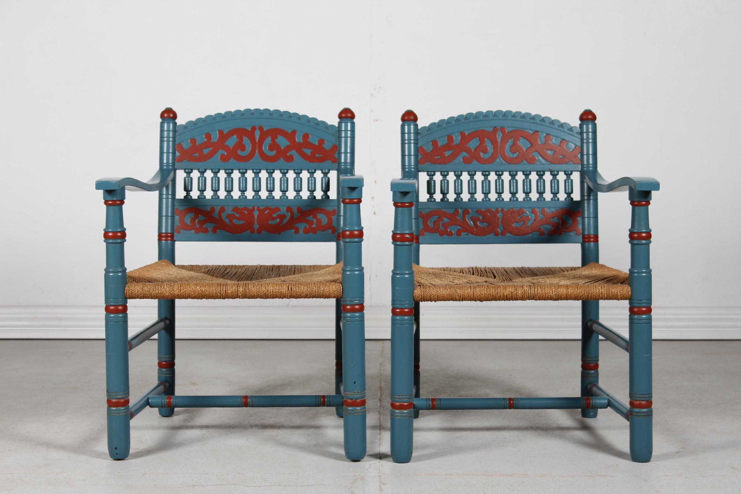 Pair of antique scandinavian country style farmer armchairs.
Handcrafted of wood by a Danish cabinetmaker in late 19th century with carvings and cord seats. 
The chairs are handpainted with blue and red paint most likely in the 1970s.

The chairs