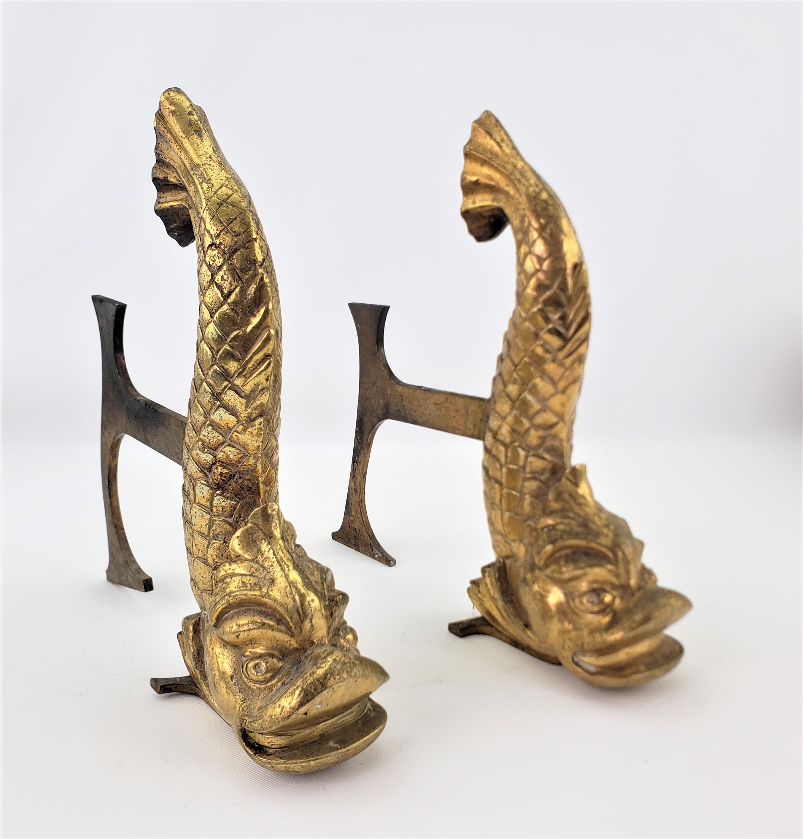 This pair of antique gilt bronze andirons are unsigned, but believed to have originated from Europe, possibly France and dating to approximately 1880. The detailed cast bronze sculptures of the andirons depict figural and stylized dolphins or fish