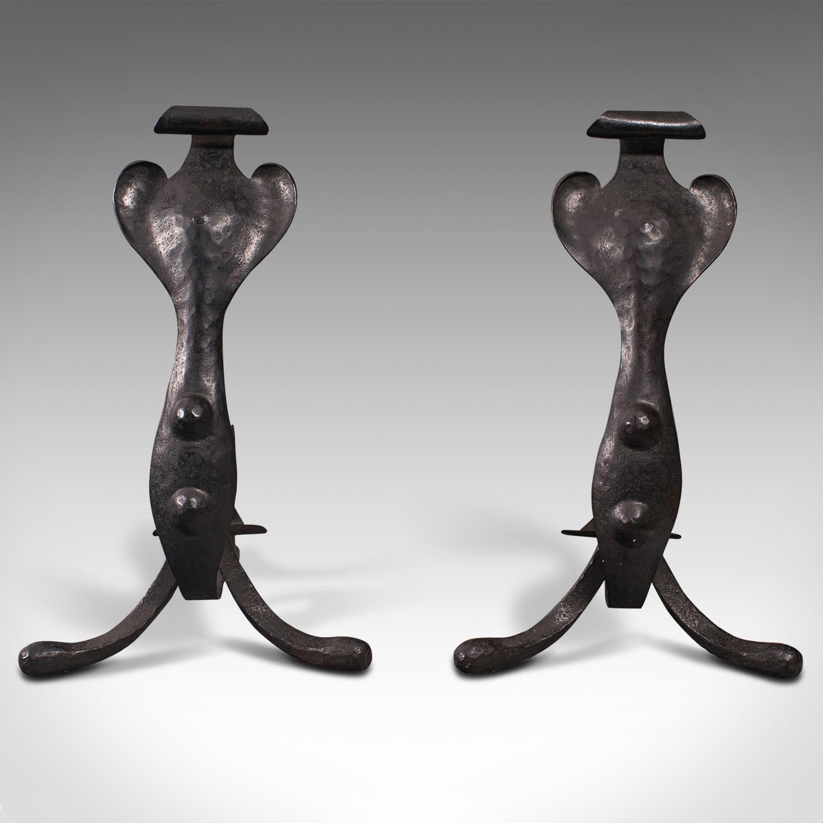 This is a pair of fireside tool rests. An English, wrought iron fire dog in Art Nouveau taste, dating to the late Victorian period, circa 1900.

Captivatingly expressive example of Art Nouveau for the fireplace
Displays a desirable aged patina