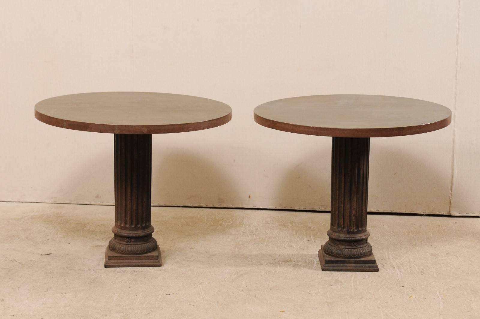 Pair of American round-shaped center tables. These American tables feature a custom 3 ft. diameter patinated steel-wrapped wooden top which is supported by an early 20th century metal fluted circular-shaped column pedestal base. These tables would