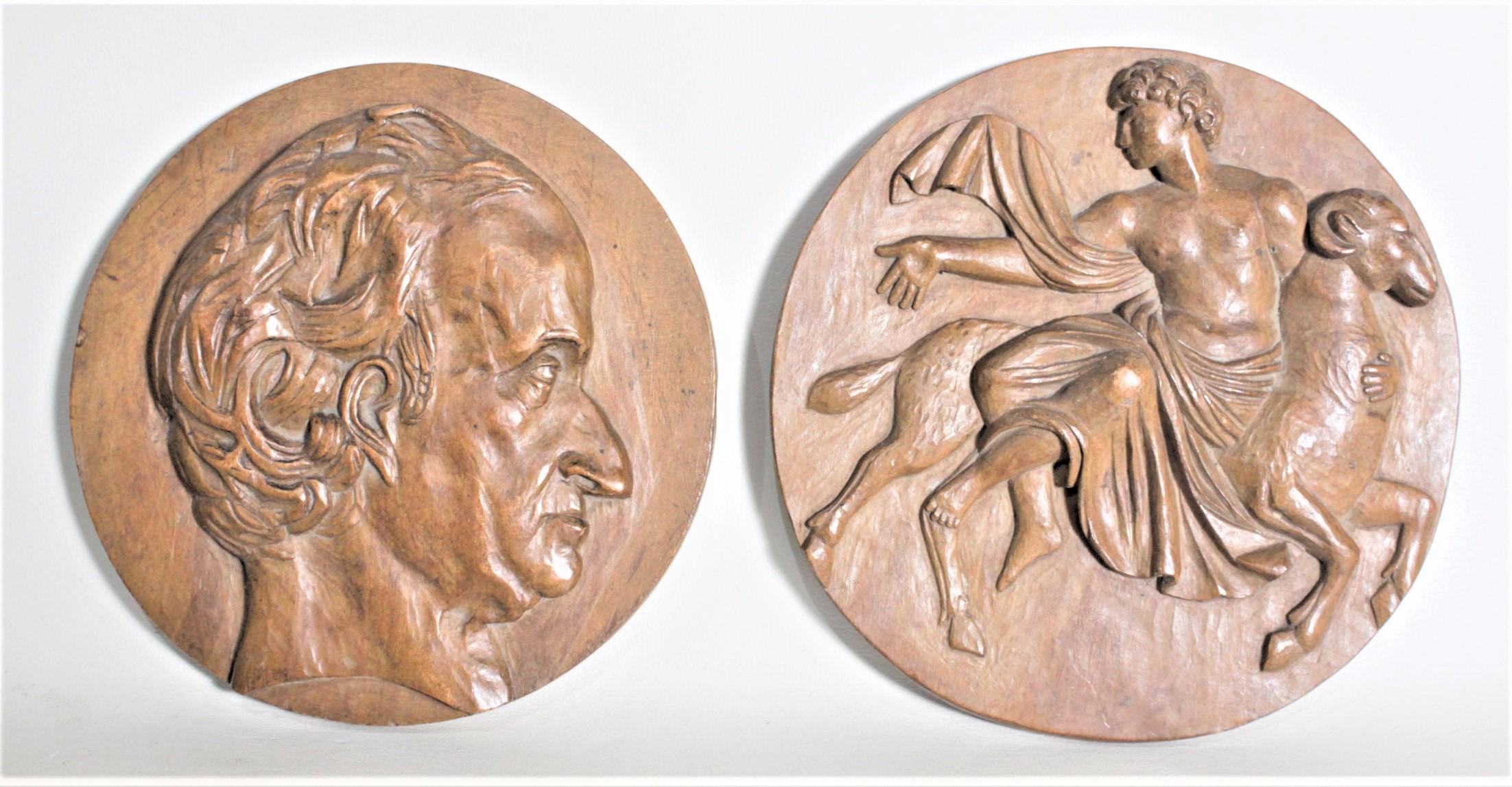 Este par de antiguas placas de pared talladas de arte popular no están firmadas, pero se cree que proceden de Grecia, aproximadamente de 1920. Estas placas murales circulares están hechas con madera blanda y una representa una escena mitológica y la
