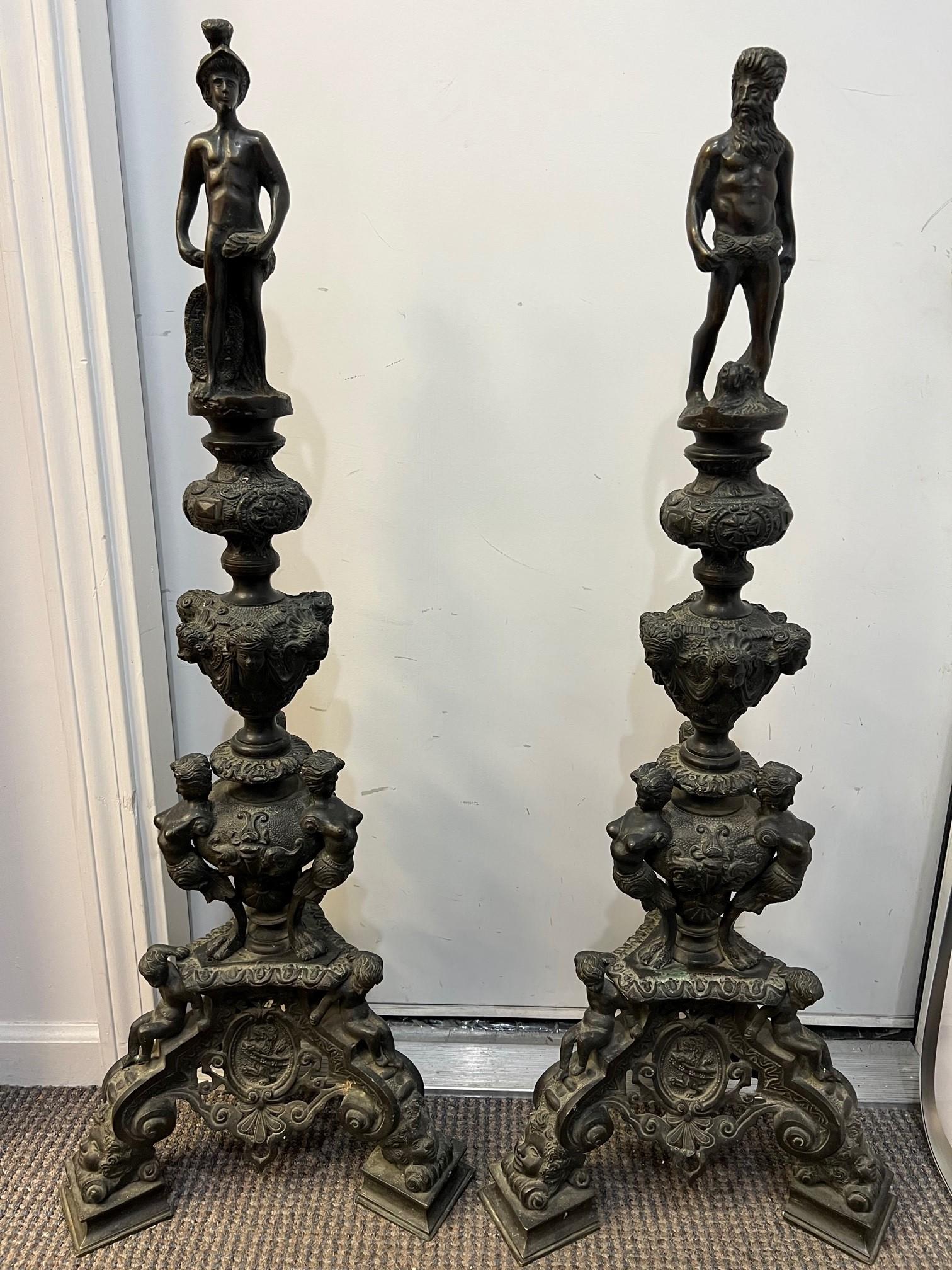 Pair of antique French 19th Century Baroque style bronze figural chenets ( Andirons ). Each chenet topped with a male figure one with a helmet and the other with a beard. The bases have cherubs with a lion crest in the center and children's faces