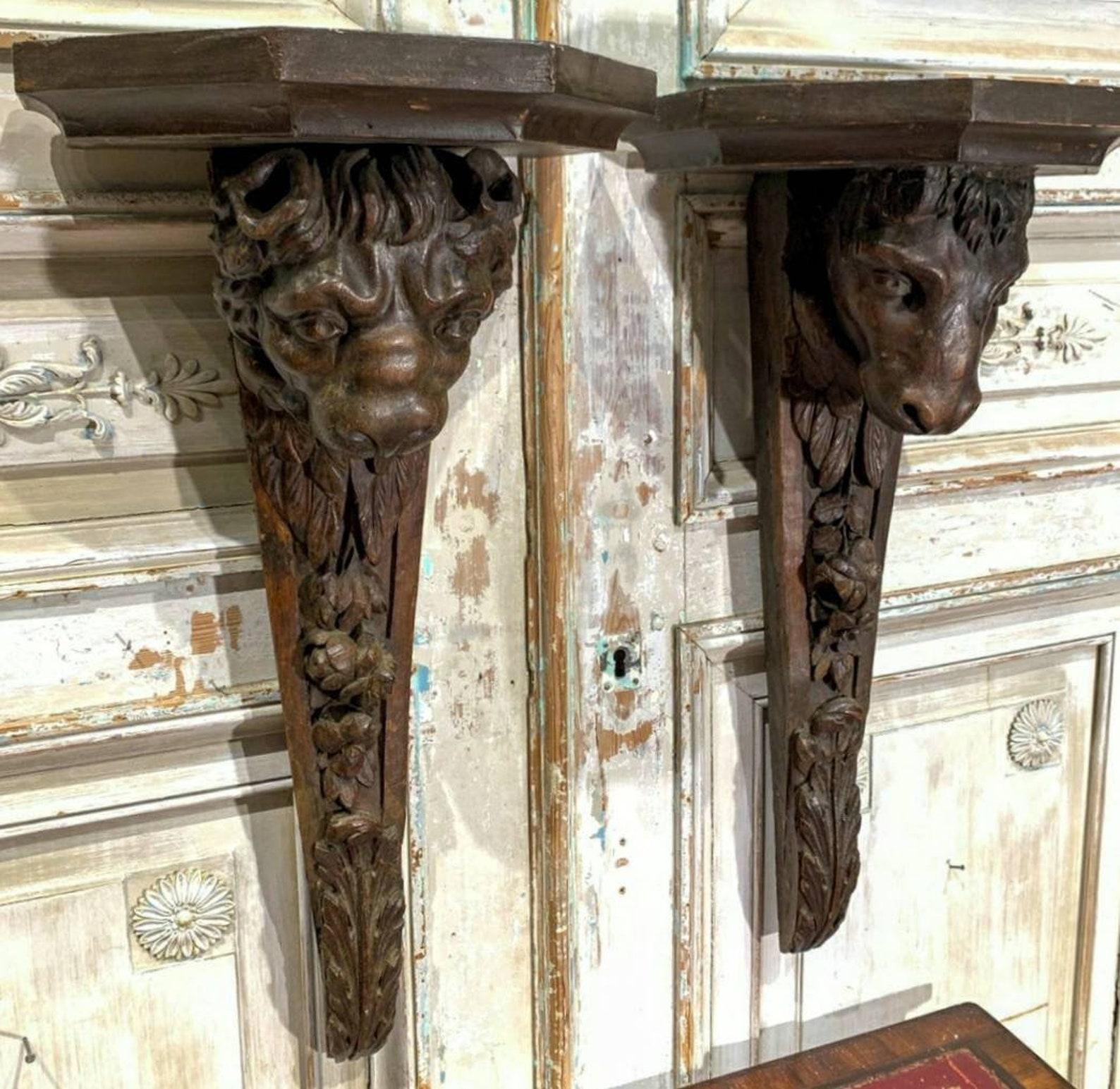 A pair of French architectural salvaged corbels, dating to the 18th to early 19th century. The large, elaborately hand carved and sculpted wooden building elements feature finely detailed figural bull and lion head over trailing fiolate motif