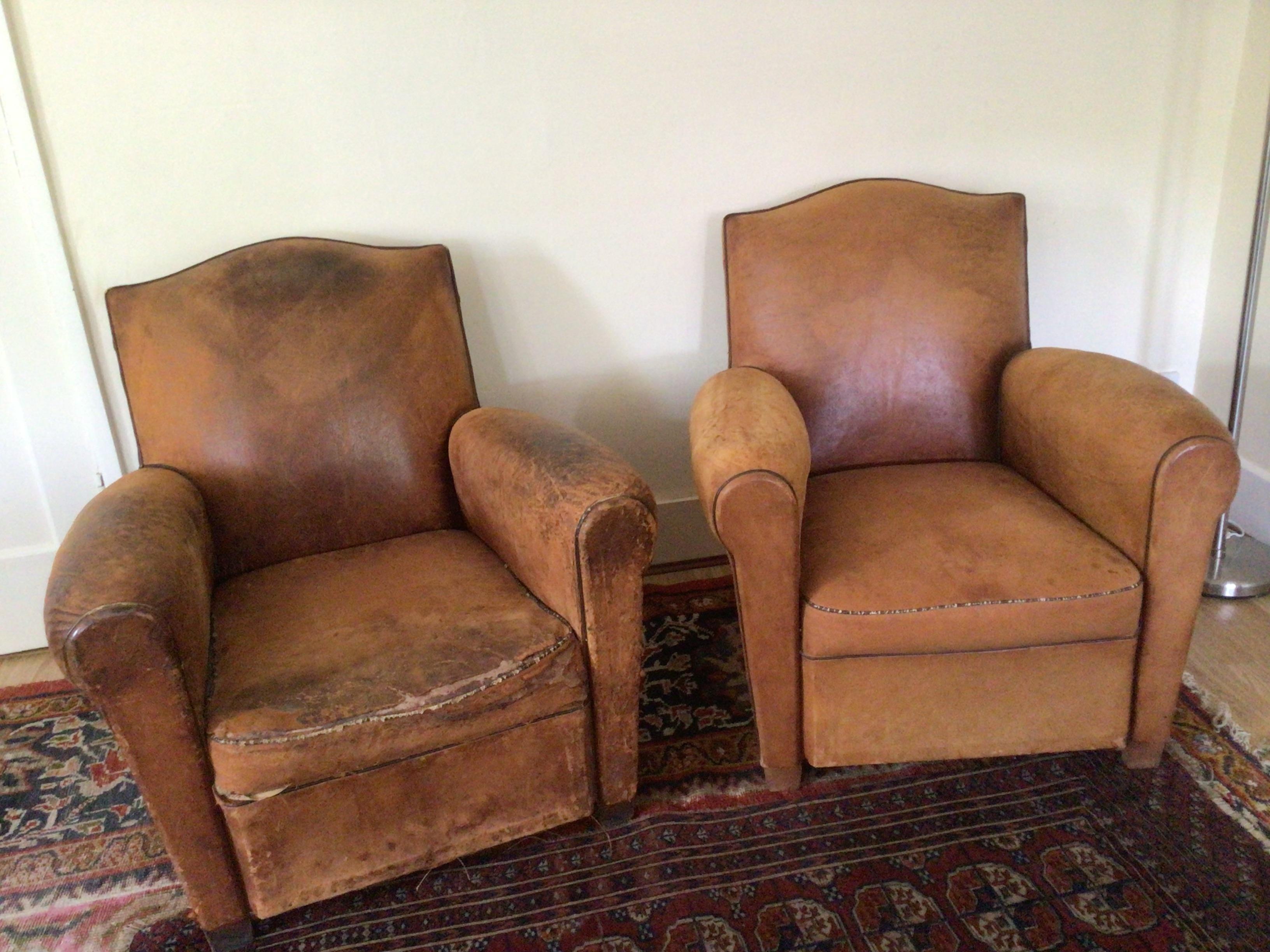 A matching pair of French, art deco leather club armchairs, they are identical in shape and size, the only difference being that one is more caramel coloured than the other.
These generous pair of antique leather club chairs benefit from a beautiful
