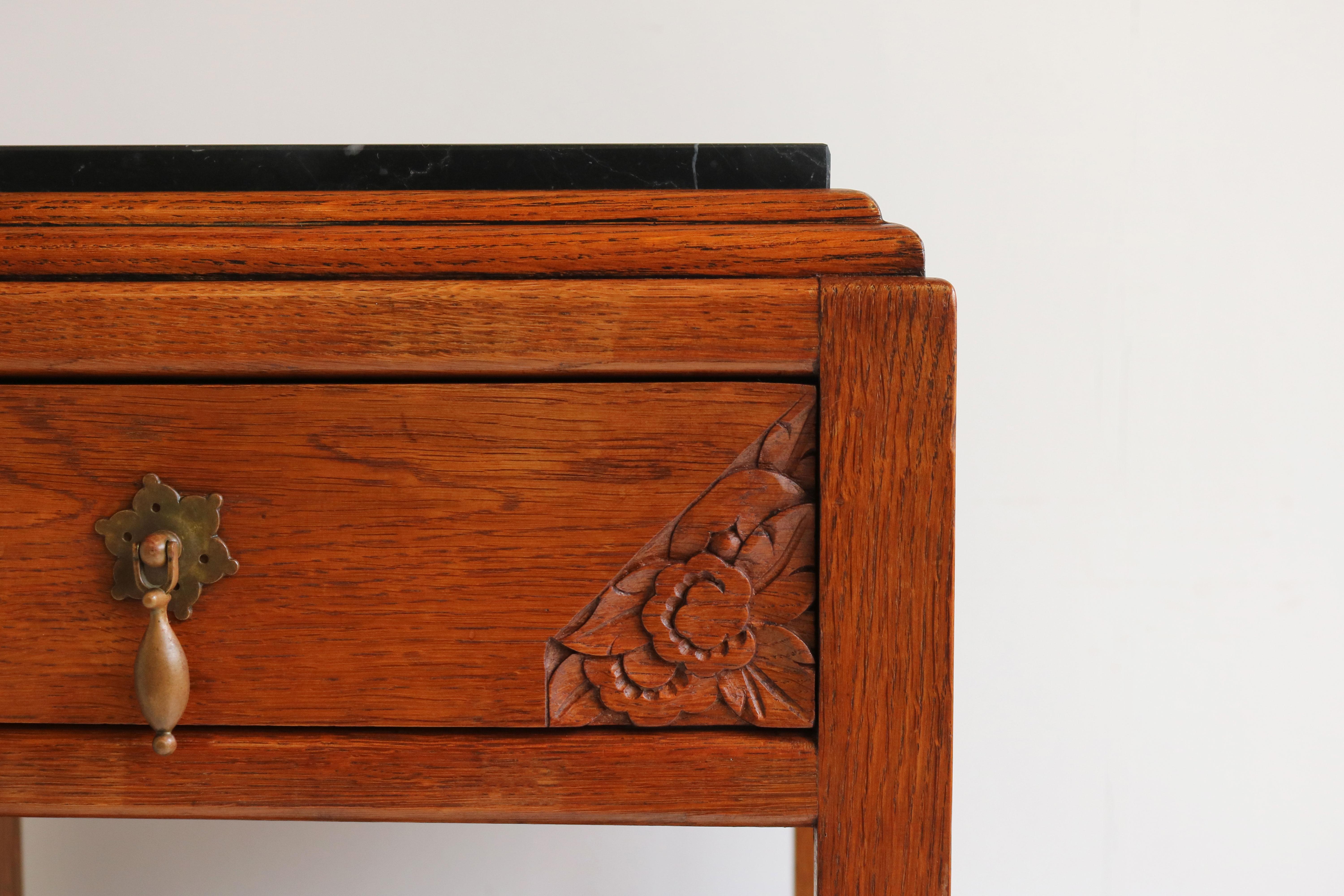 Marvelous & Charming ! This pair of French Antique Art Deco nightstands / bedside tables from the 1920s. 
Gorgeous patinated oak with Black marble tops in the Art Deco design style. 
Lovely Art Deco details with geometric floral carvings ! 
The