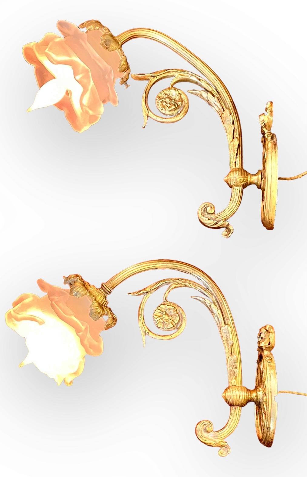 Pair of French Art Nouveau Gilt Bronze Wall Sconces
This elegant pair of small gilt bronze wall lights are decorated with ribbons at the top of the oval back plates having stylized  leaves. The arms having delicate vine tendrils with medallions