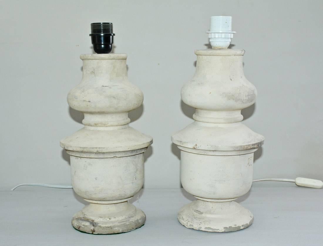 Great looking pair of shaped column form on round base. Made of antique cast stone balustrade from French Chateau.  Lamps comes with Belgium linen shades. Lamp sockets are two different colors but does not effect overall height of lamps. Sockets are