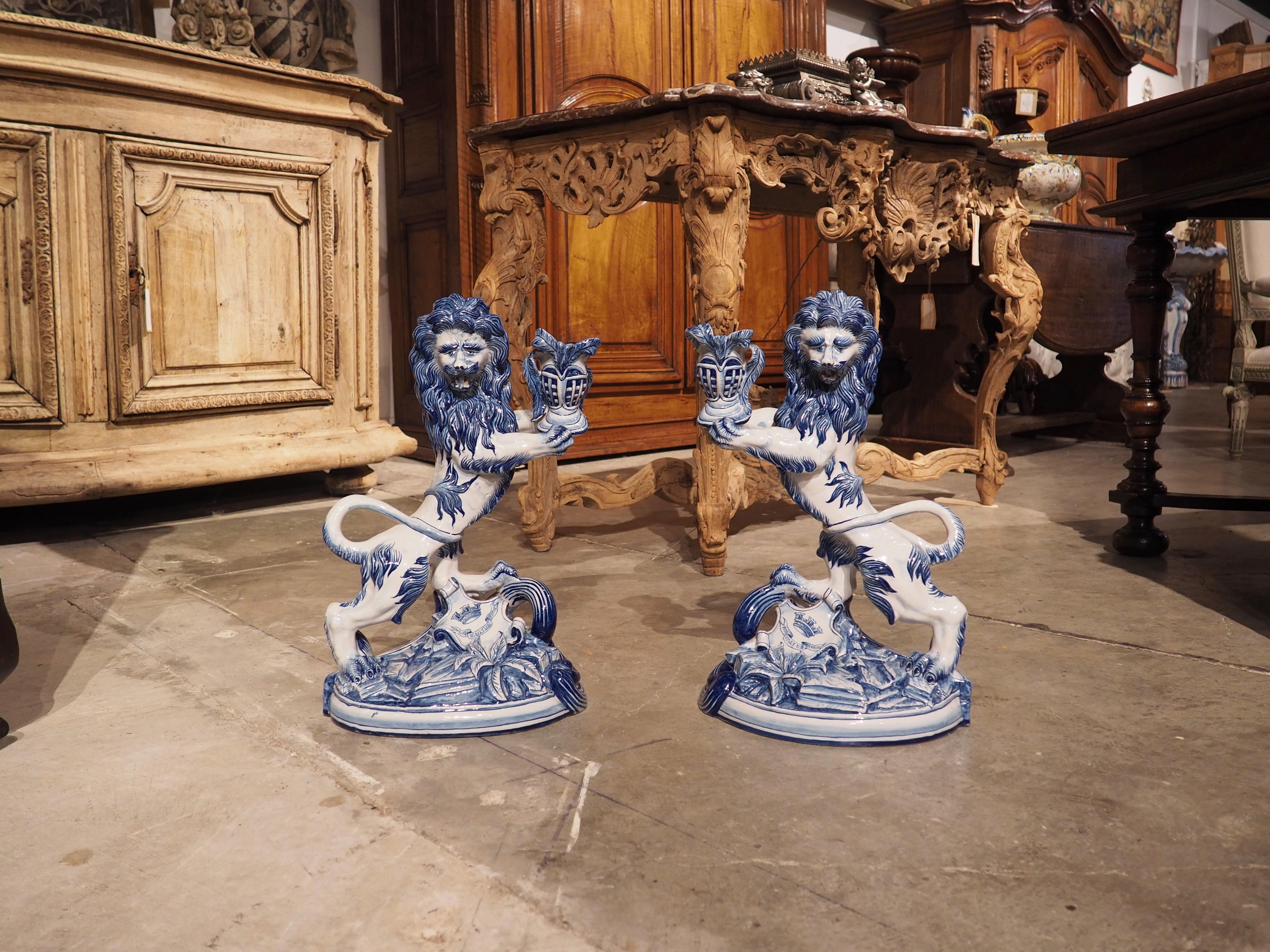 A beautiful pair of hand-painted cobalt blue and white candle holders, these faience lions date to circa 1890. Based on production marks located under the rear paw of each lion, the candle holders were produced in Saint-Clément, by Keller & Guerin,