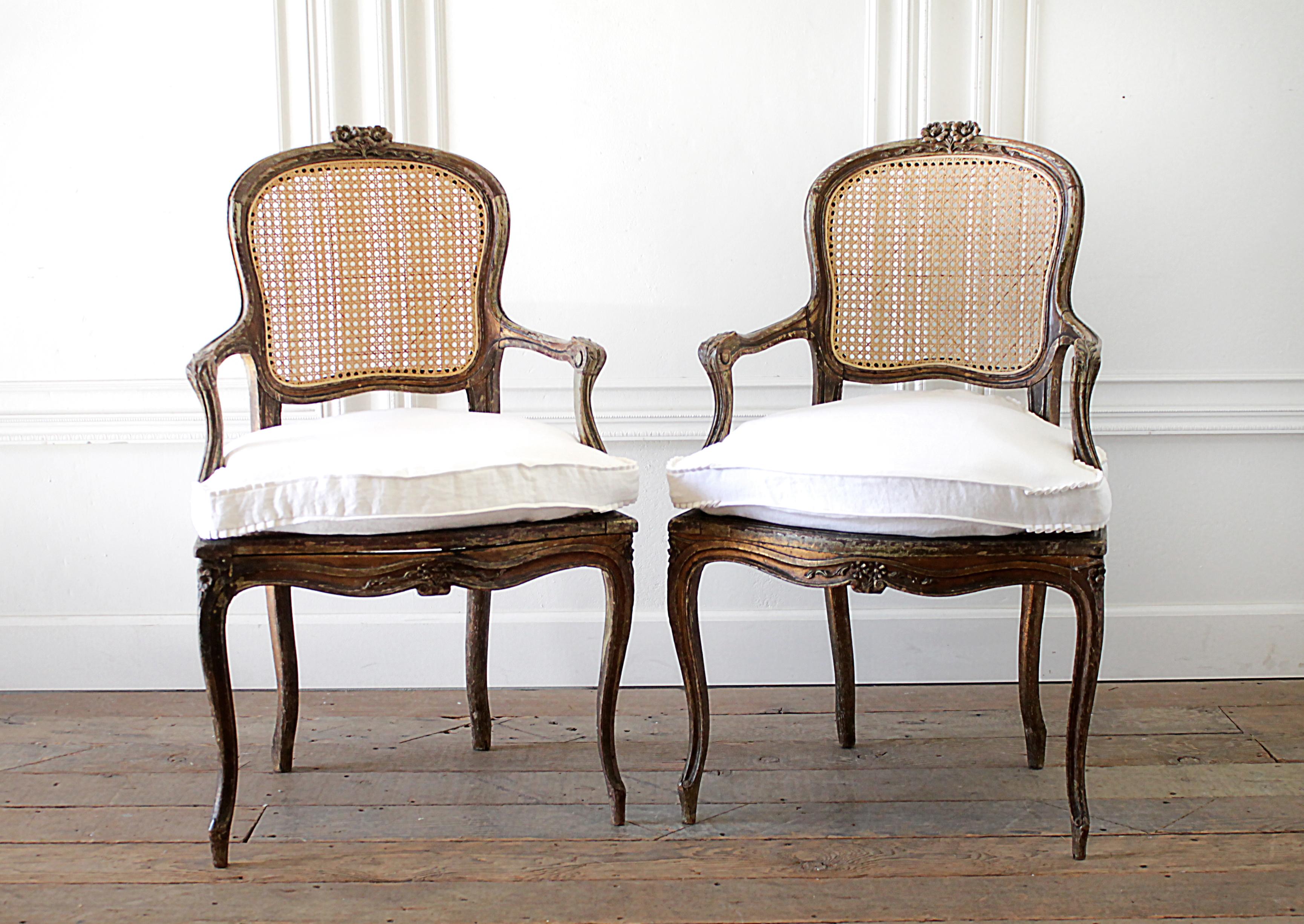 Pair of antique French cane back open armchairs with custom linen cushions
Natural aged wood with a wonderful distressed patina. The cane looks to be newer, must have been replaced at one point. The cane is a light unstained color. 
The cushions