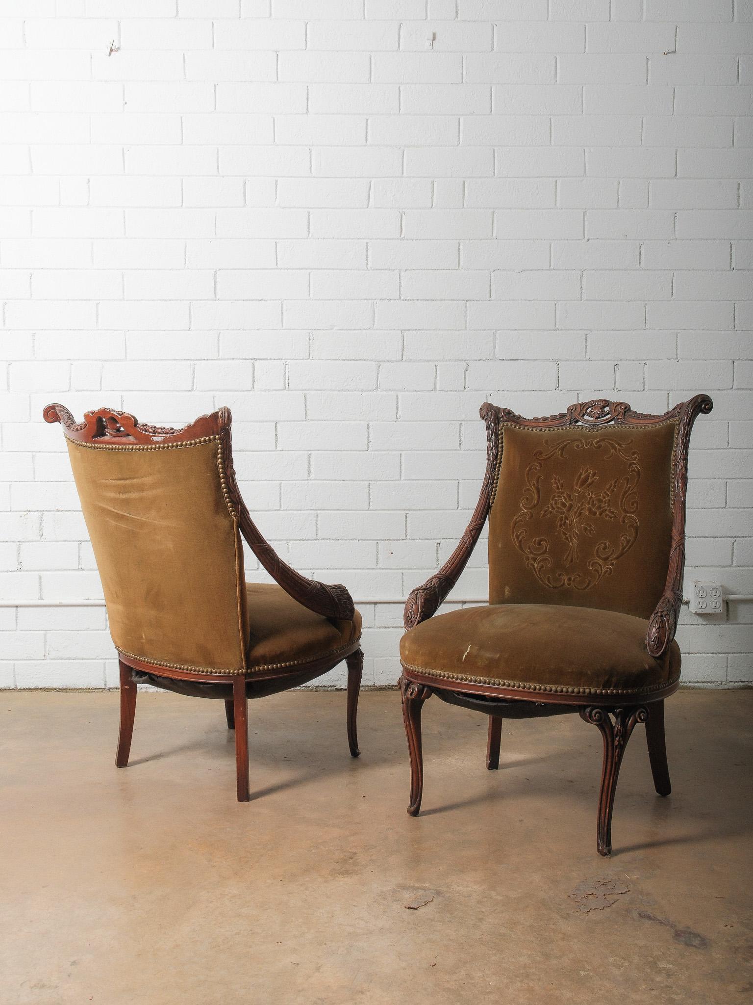 Un'elegante coppia di antiche poltrone francesi in noce intagliato con tappezzeria originale in velluto e squisiti dettagli intagliati a mano. Ogni sedia presenta uno splendido schienale sagomato con motivi floreali e a volute, braccioli e gambe