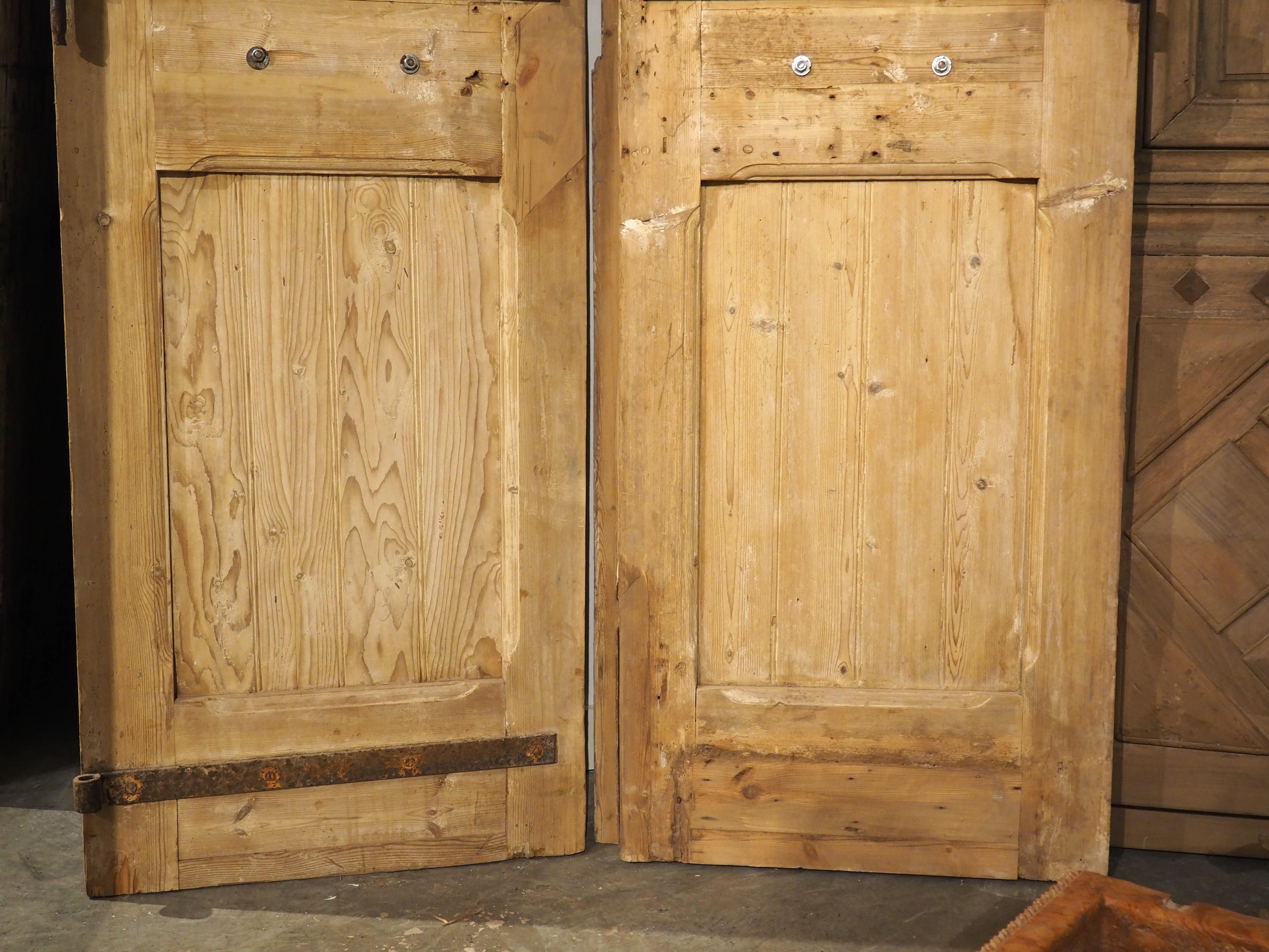 Diese Flügeltüren aus dem Jahr 1880 zeichnen sich durch außergewöhnliche Flachreliefschnitzereien aus, die mit ebenso beeindruckenden Eisenbeschlägen kombiniert sind. Die asymmetrischen Fenster, die von sehr dicken Leisten umgeben sind, sind mit