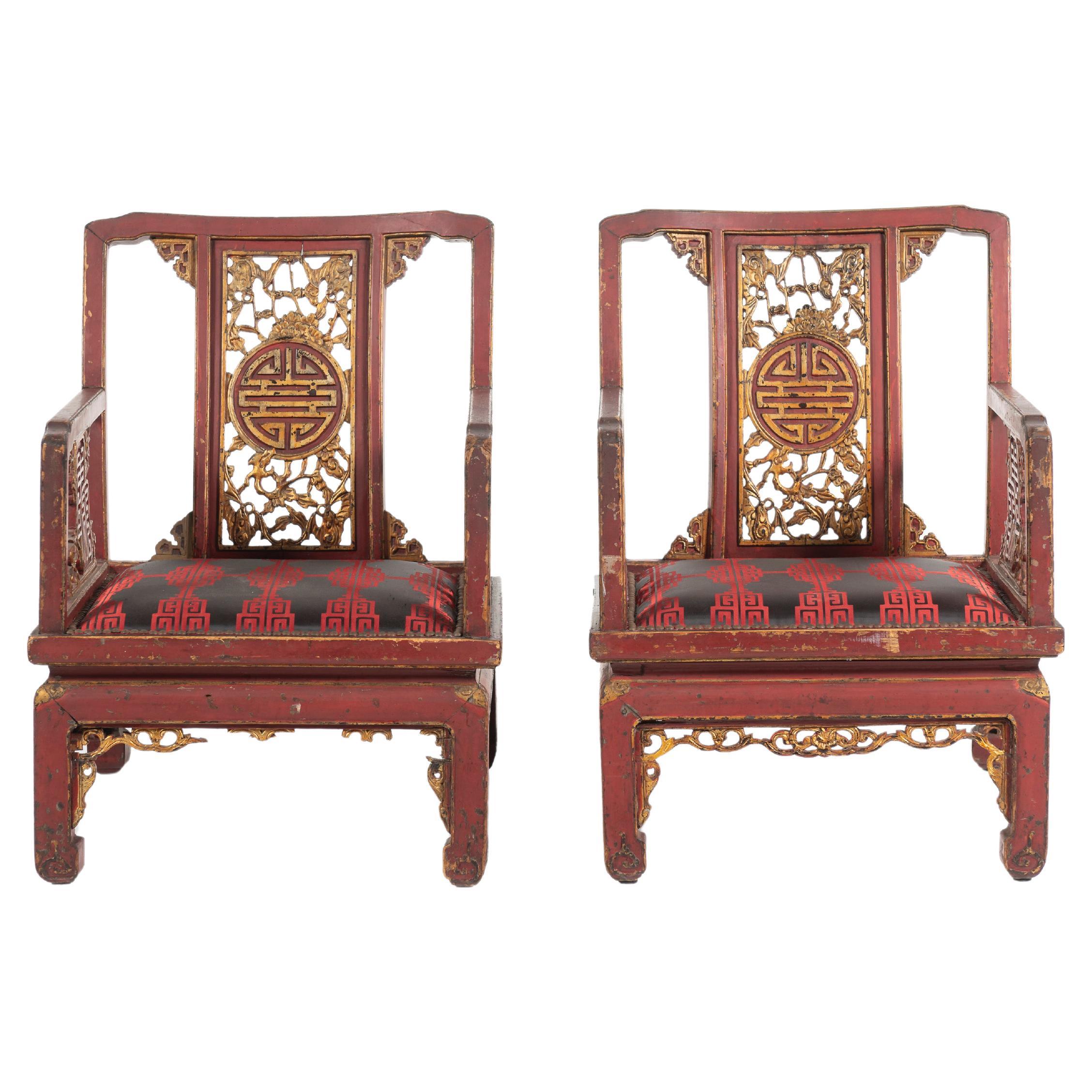 Paire d'anciennes chaises à accoudoirs de style Chinoiserie française de la fin du 19ème siècle. Ces chaises grandioses sont peintes en rouge chinois avec des applications décoratives en or sur les motifs ajourés traditionnels. Munies de coussins en