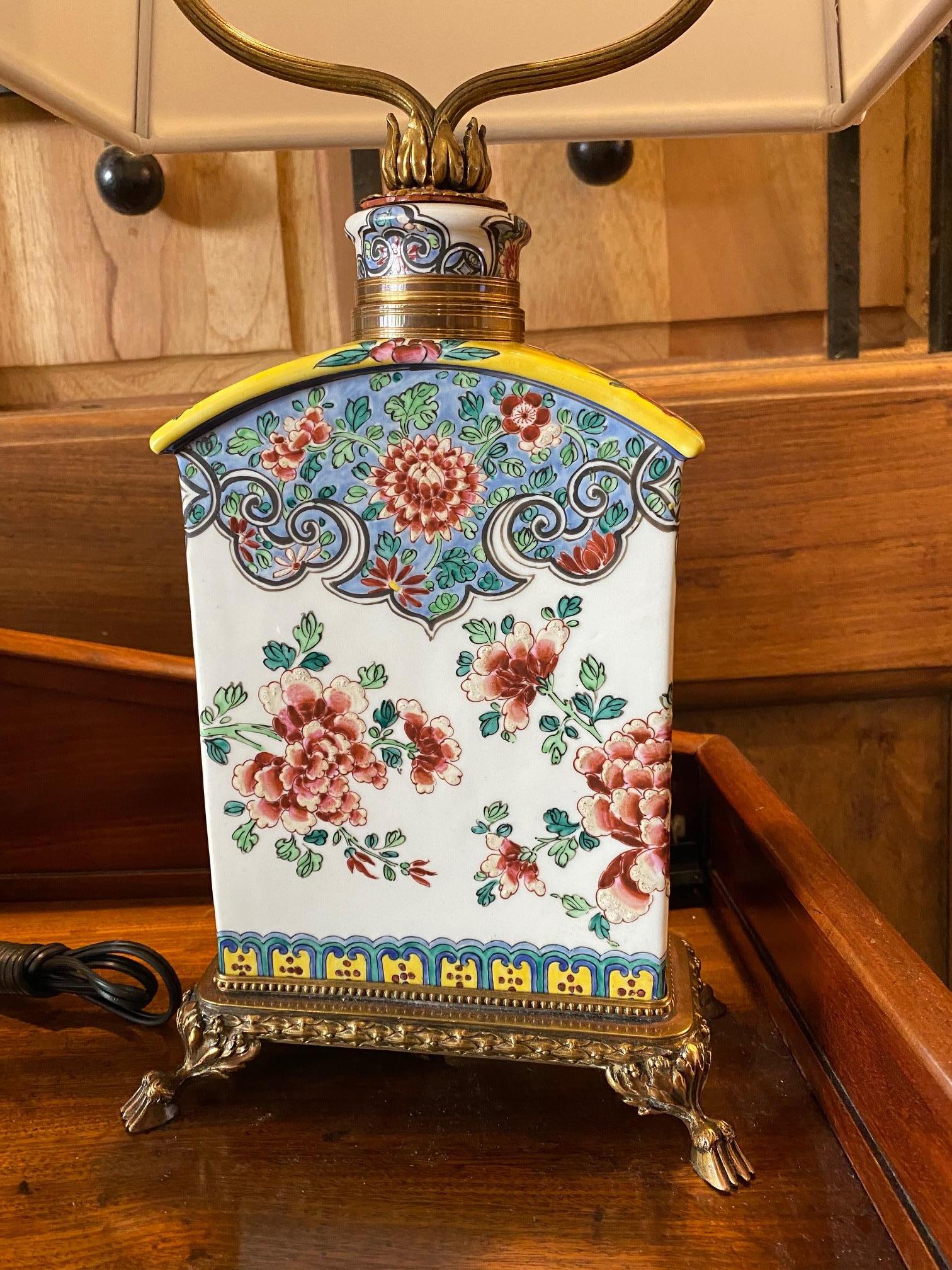 This pair of Chinese tea caddy table lamps where brought to French and mounted into bronze dore' trim hand painted in the chinoiserie design of flowers (I think a stylized Phoenix with chrysanthemums on each) enamel on porcelain very unique style