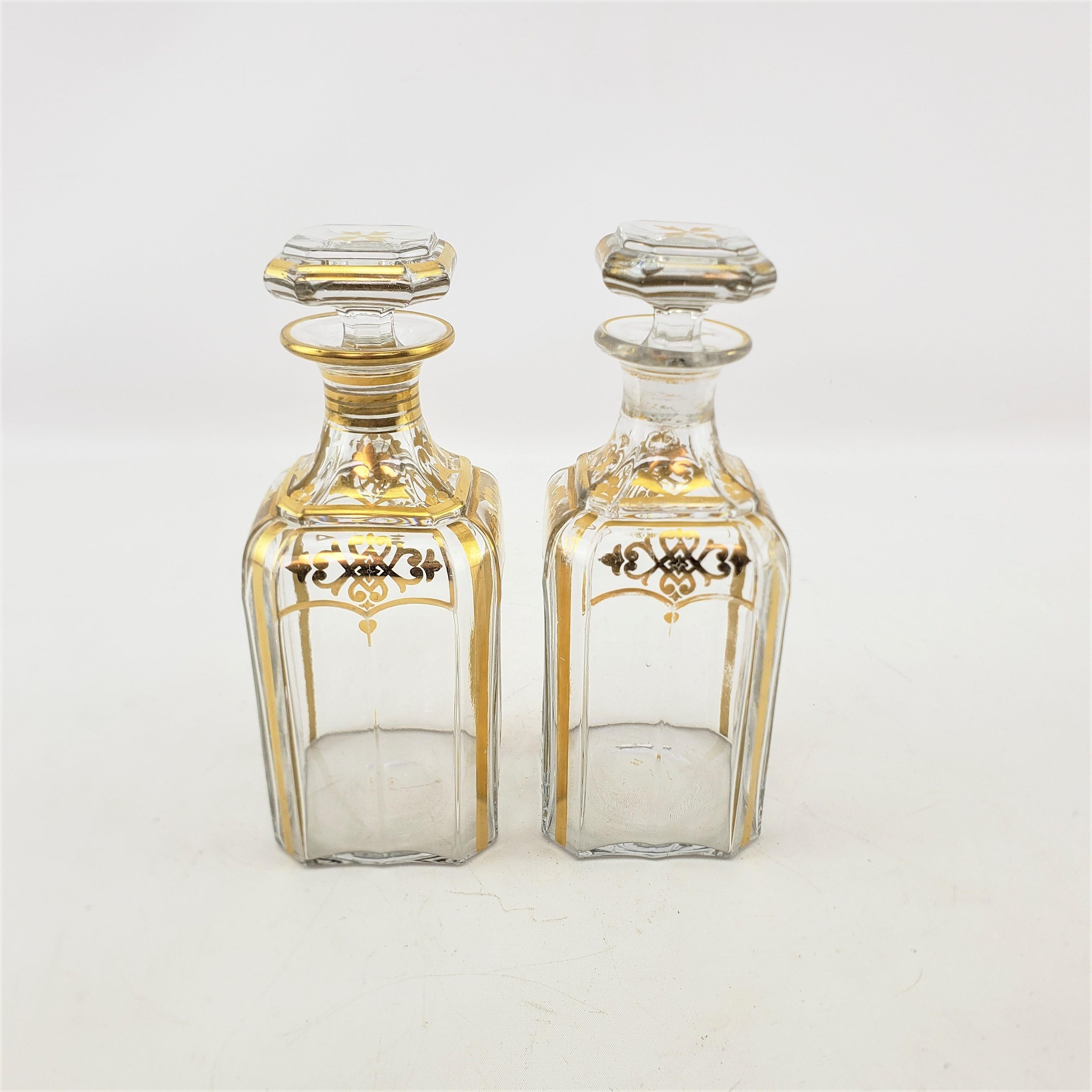 This pair of antique liquor bottle decanters are unsigned, but presumed to have originated from France and date to approximately 1900 and done in an Empire Revival style. The decanters are done with a clear crystal with clear stoppers which have