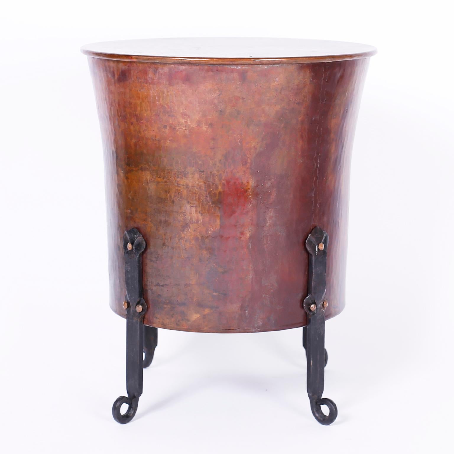 Pair of copper and Iron stands with hand-hammered copper tapered drums having acquired a lofty patina and riveted to four hammered graceful iron legs. We have another pair available if you are looking for 4 tables.