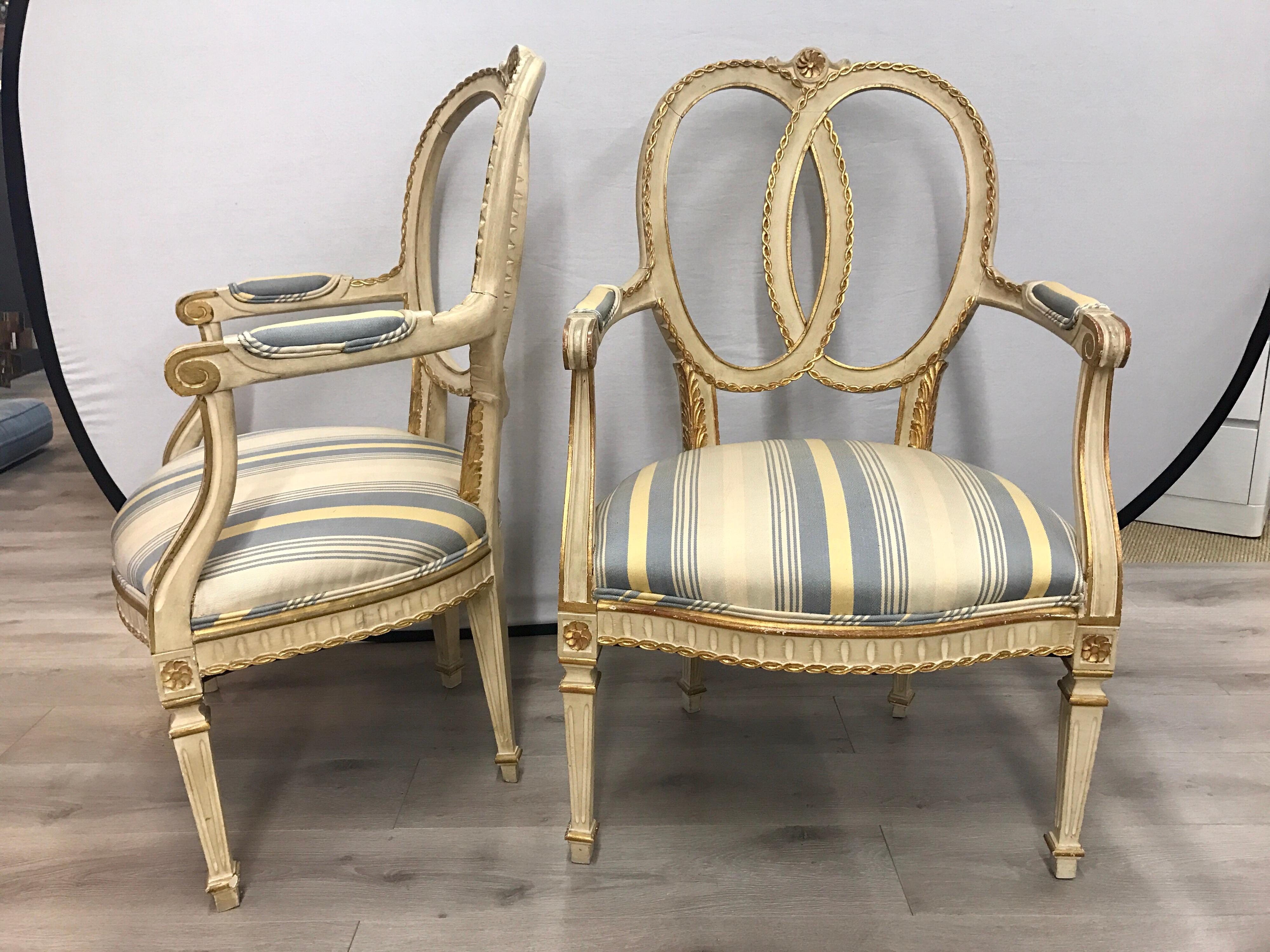 Elegant pair of French cream and gold painted armchairs with blue and pale yellow striped upholstery. Gorgeous aged patina.