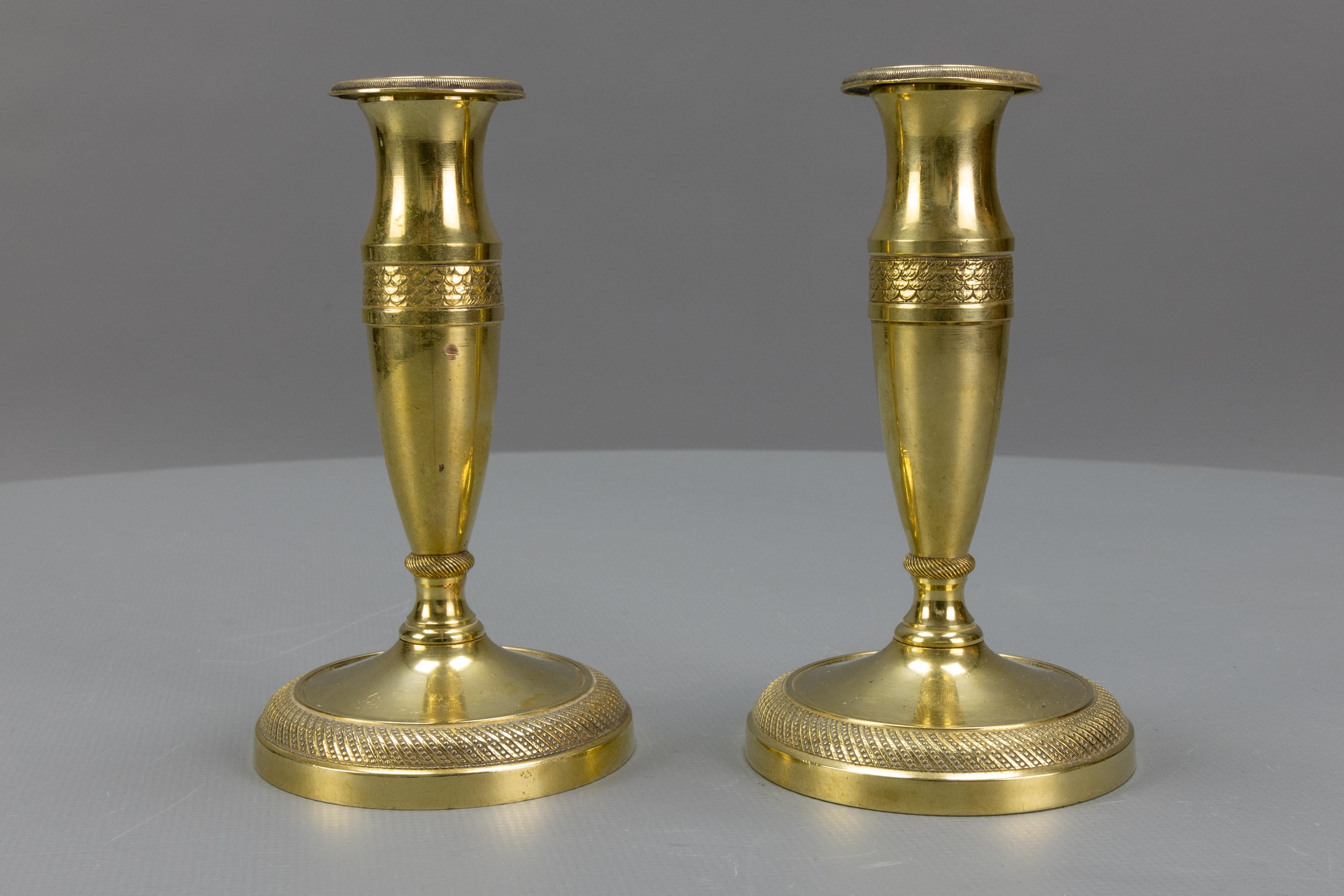 Pair of antique French Empire-style gilt brass candlesticks from ca. 1890.
A beautiful and compact-sized pair of French Empire-style gilt brass candlesticks with removable bobeches (drip trays).
These antique candlesticks will make a wonderful