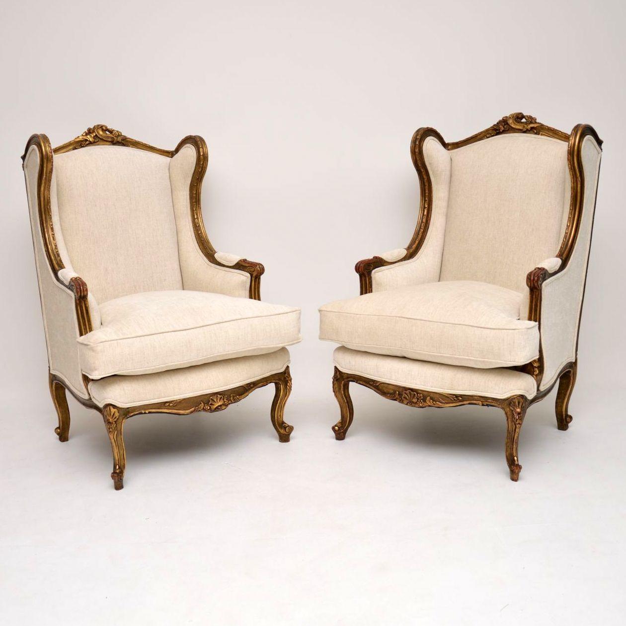 Original pair of antique French giltwood framed wing armchairs in good original condition, which have just been re-upholstered in our very popular cream linen fabric, with double piping. The gilt work finish is naturally aged and you can see the red