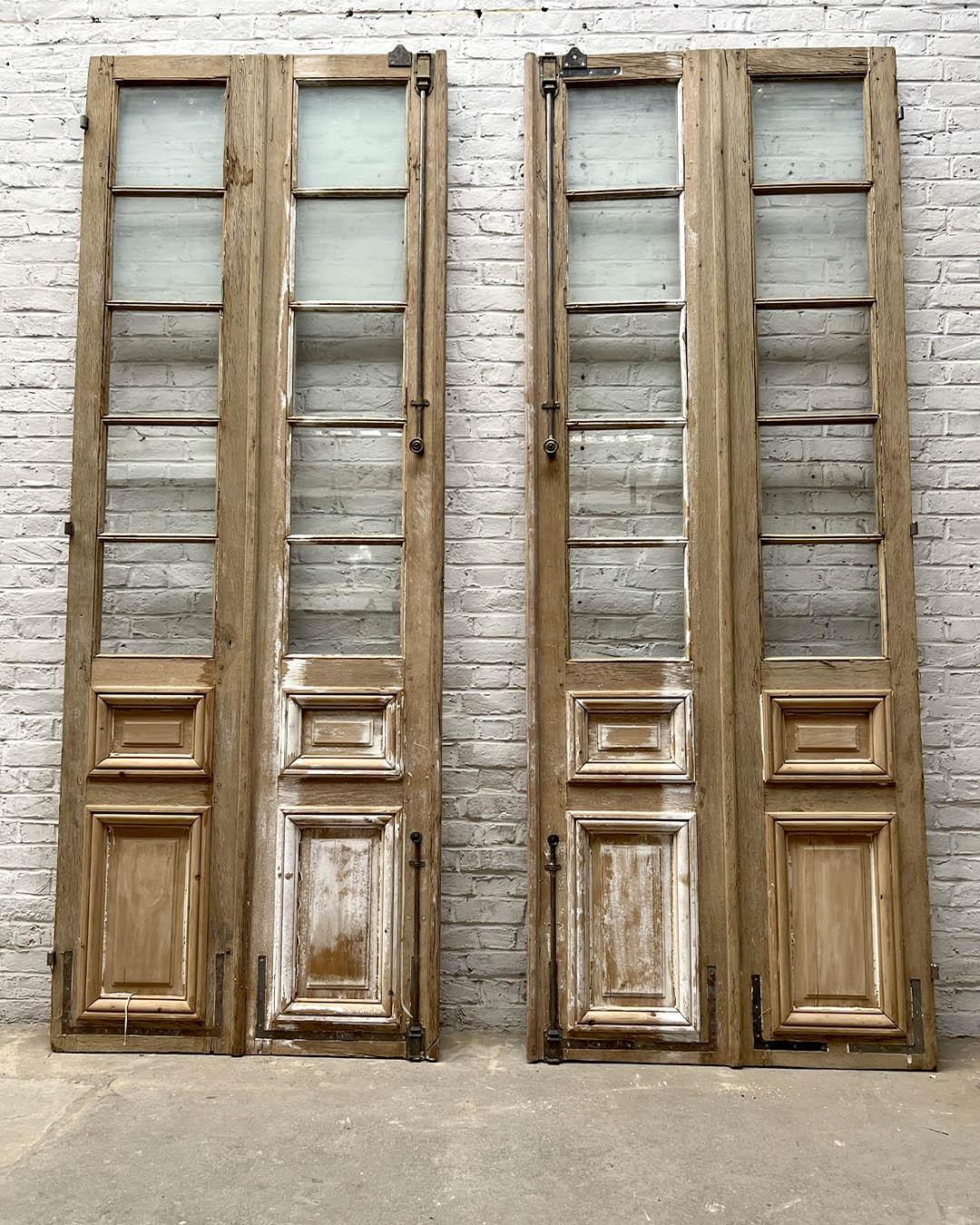 egante coppia di porte francesi vetrate risalenti agli inizi del XX secolo. Realizzate in legno con pannelli modanati nella parte inferiore e lastre di vetro multiple nella parte superiore, queste porte presentano una patina naturale invecchiata con