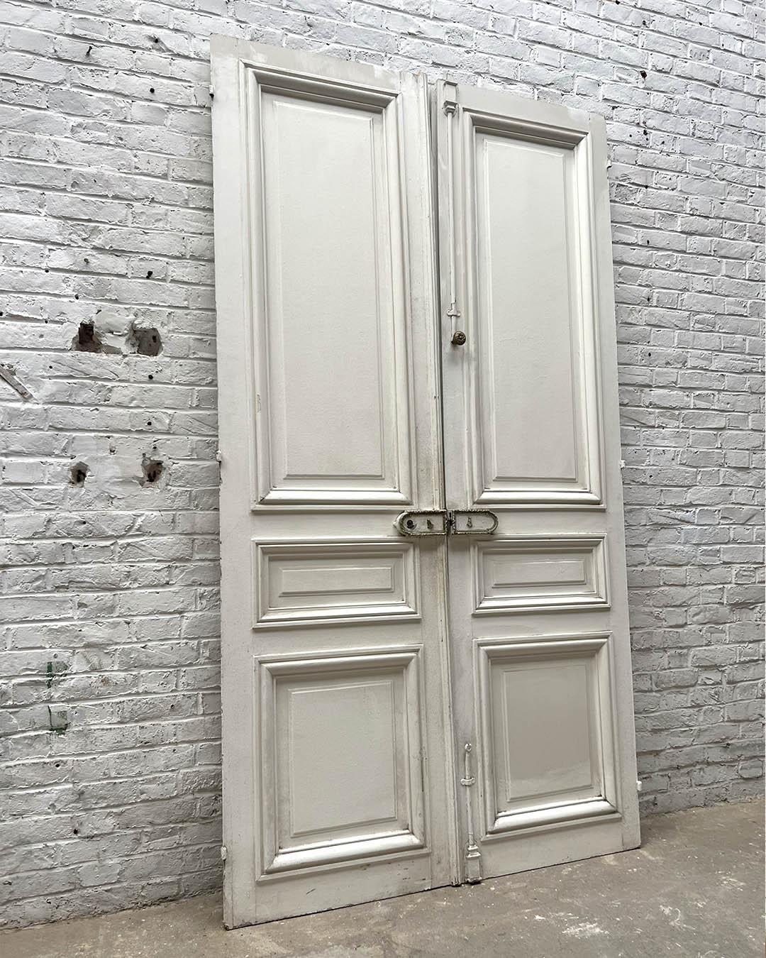 Elegante coppia di porte doppie francesi haussmanniane risalenti ai primi anni del XX secolo. Realizzati in legno con pannelli in rilievo e modanati, presentano una patina originale e un raffinato stile architettonico parigino. Queste porte