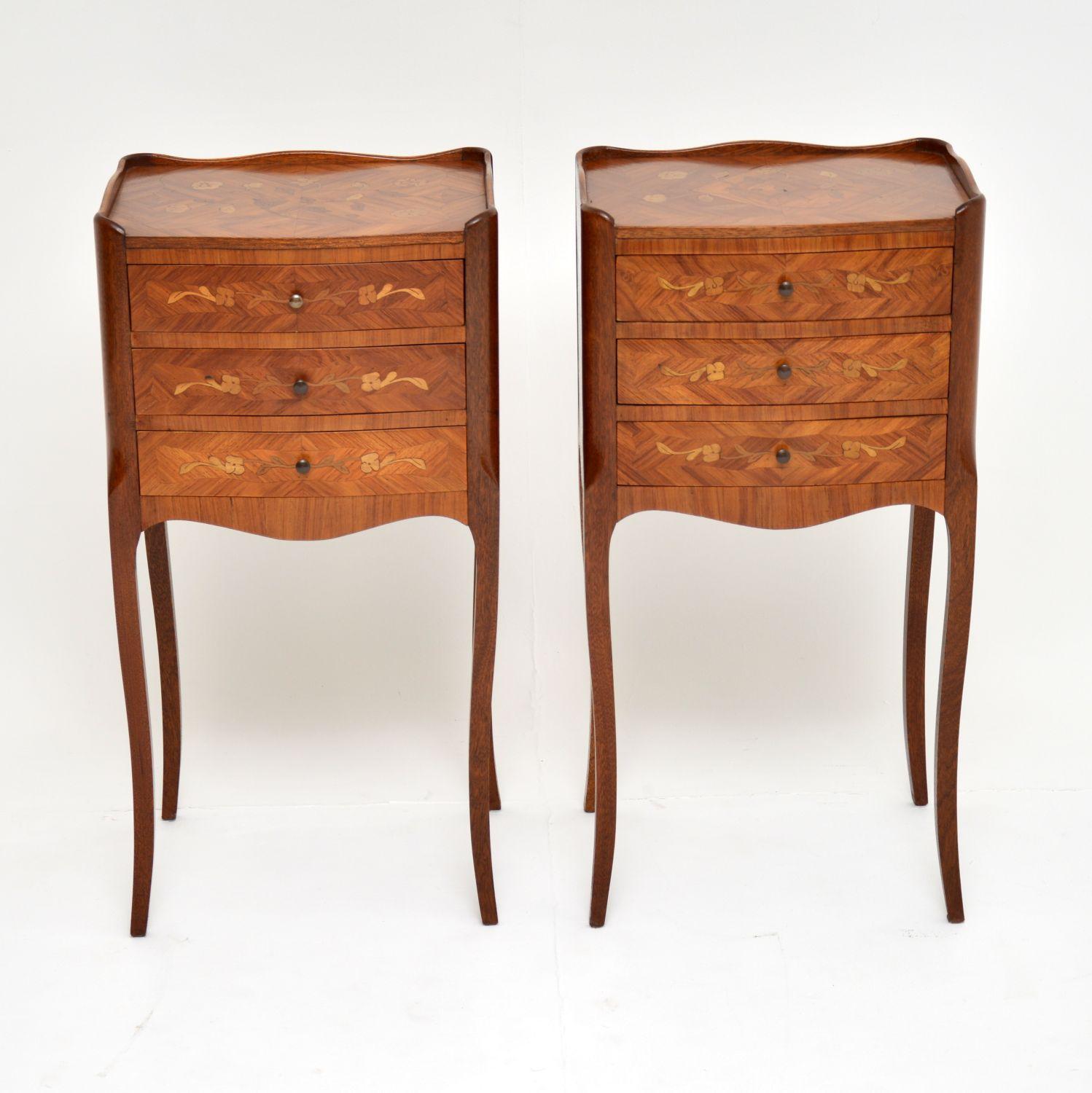 Paire de tables de chevet anciennes de style français à trois tiroirs sur d'élégants pieds, en bois de roi avec de fines incrustations florales et de la marqueterie sur les plateaux et sur les façades des tiroirs. Les dos sont également finis et