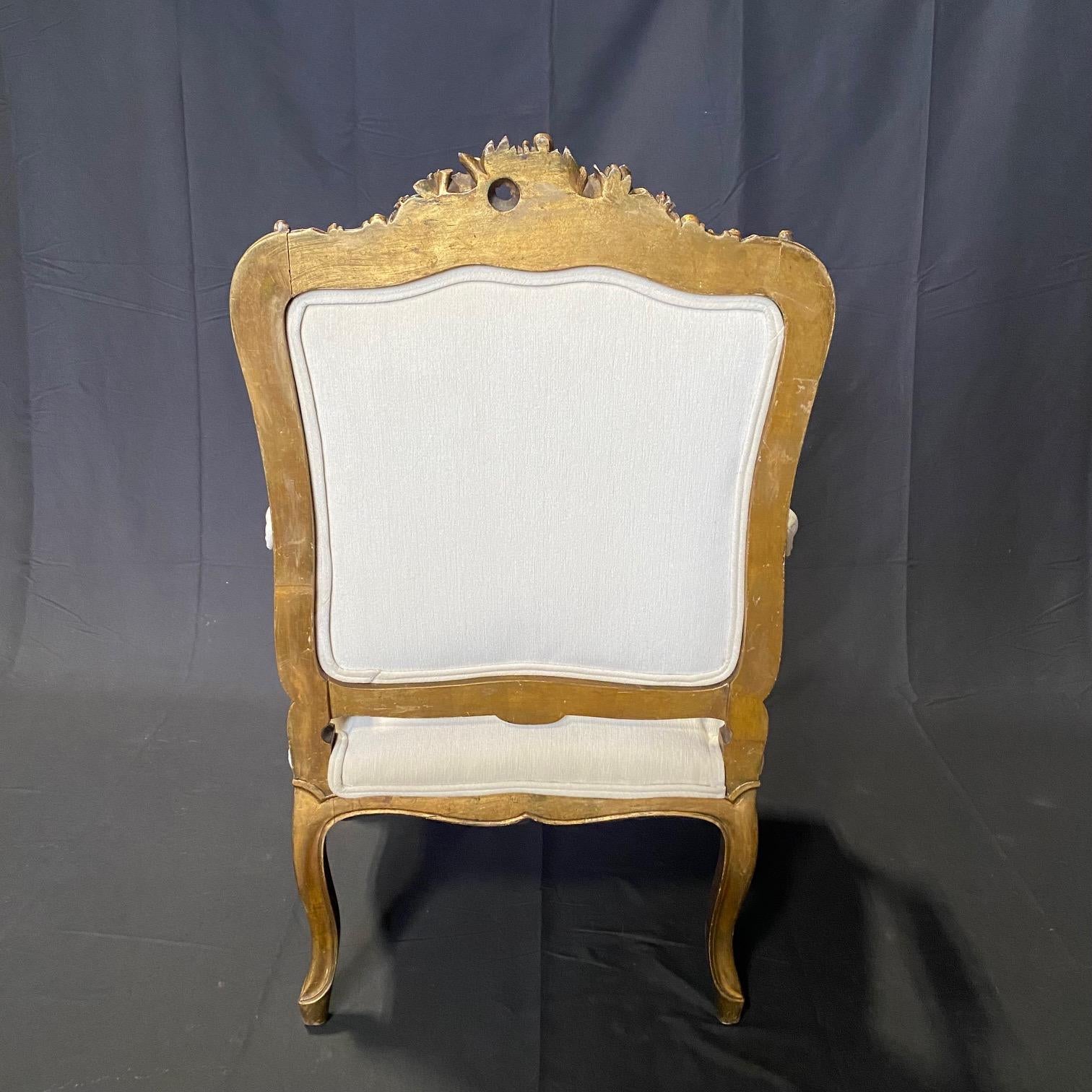This pair of fauteuil armchairs, newly upholstered in neutral fabric, is very elegant, with exquisitely carved, elegant back rests, aprons and armrests. Antique sturdy frame, original gold gilt paint with exquisitely carved gilt gold accent overlay,