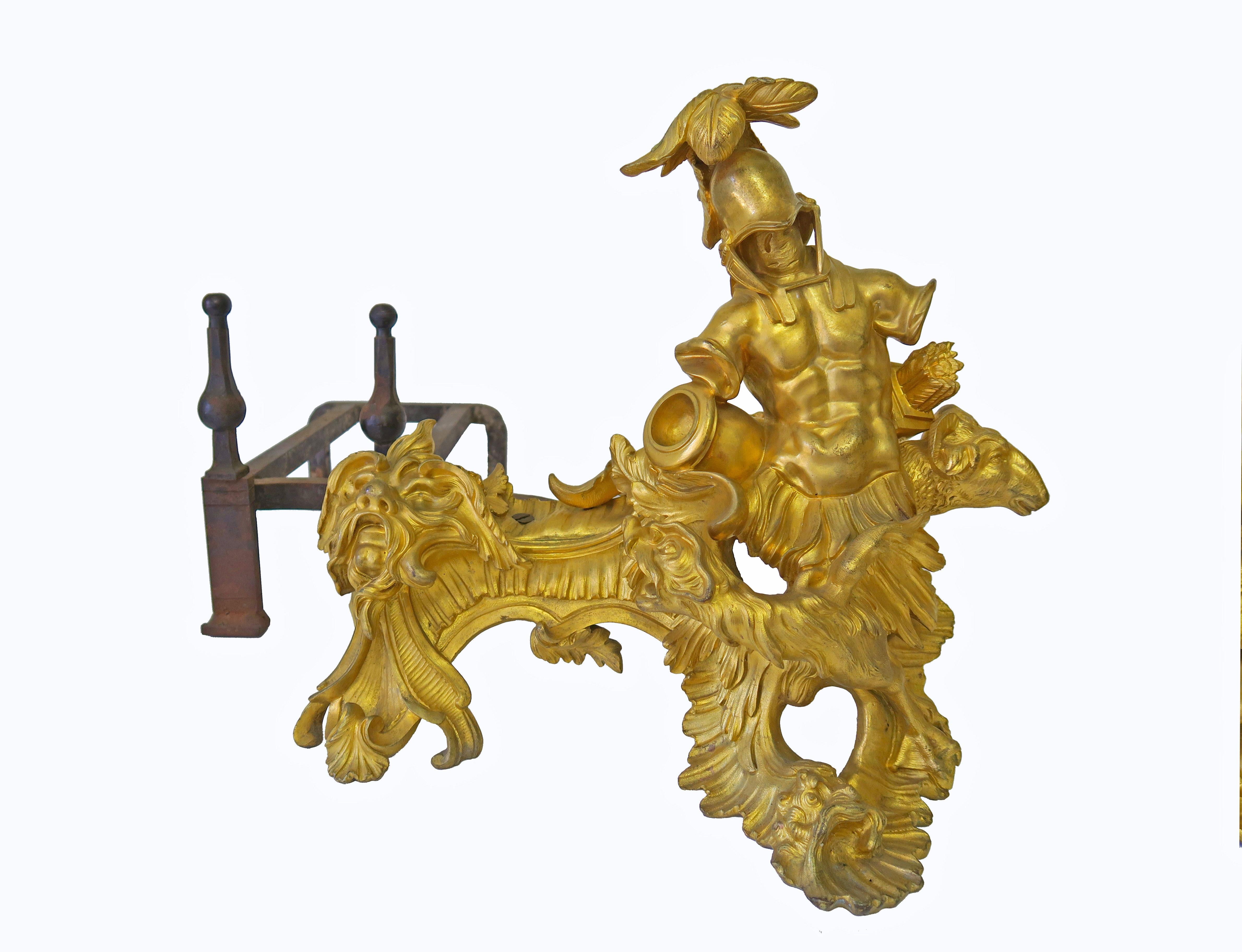 An important pair of 18th c. French Louis XV ormolu chenets. Each cast as military trophy, one with the feathered Turban, canon and boar, the other with a feathered helmet, quiver and ram, supported by cast-iron billet bar. An 18th century pair of
