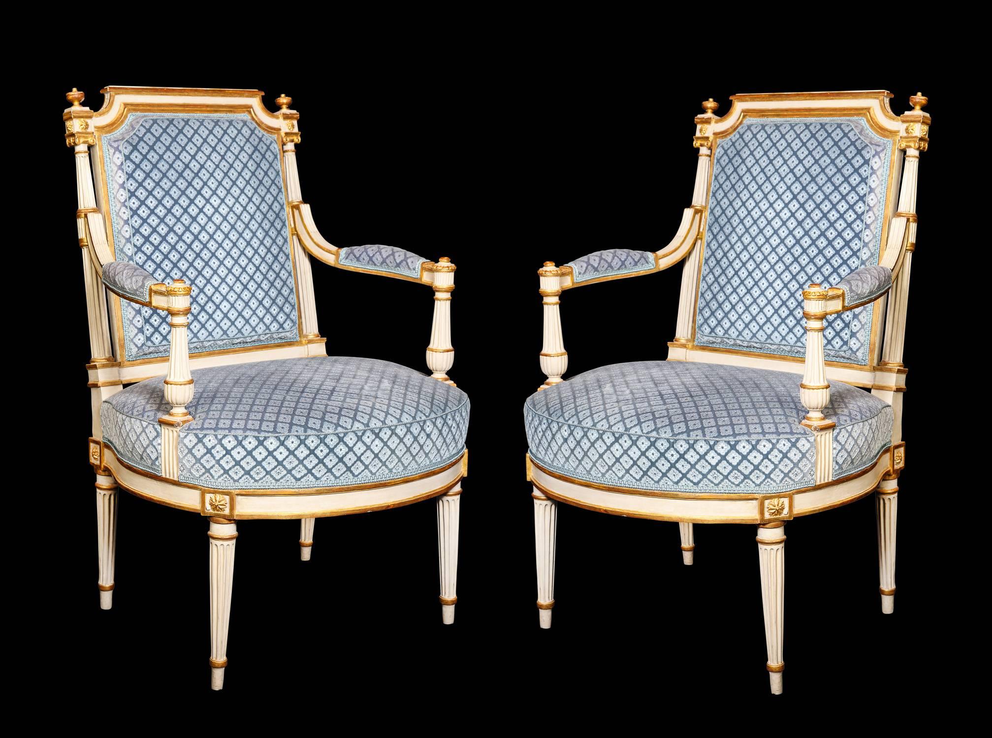 A pair of exquisite antique French Louis XVI carved giltwood and white painted armchairs of exceptional workmanship and quality upholstered in blue velvet fabric, 18th century.