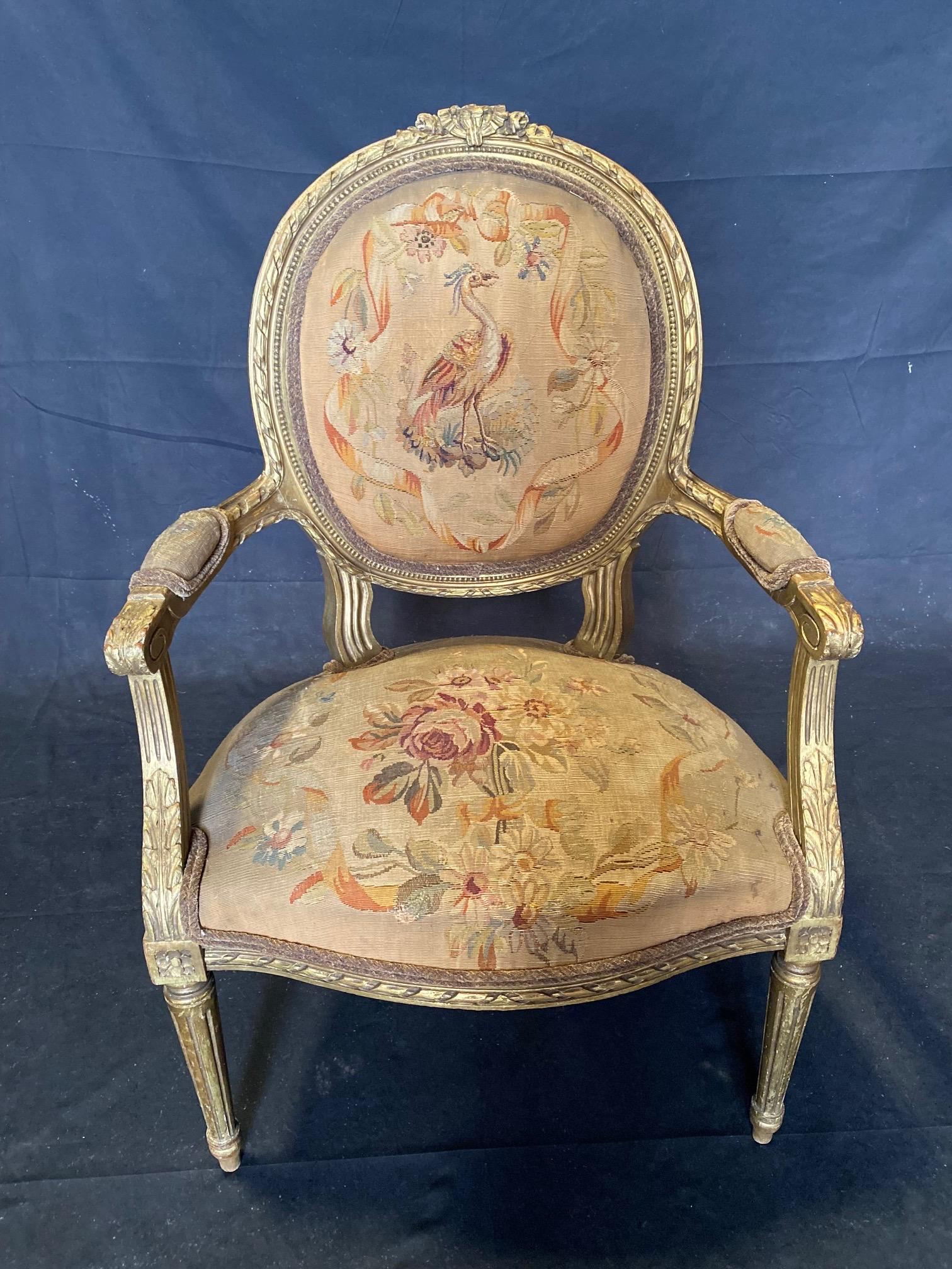 Upholstered in fine Aubusson tapestry fabric, this pair of early 19th century French Louis XVI matching armchairs or fauteuils  have carved giltwood  frames and finely woven Aubusson tapestry upholstery playfully illustrated with bird scenes and