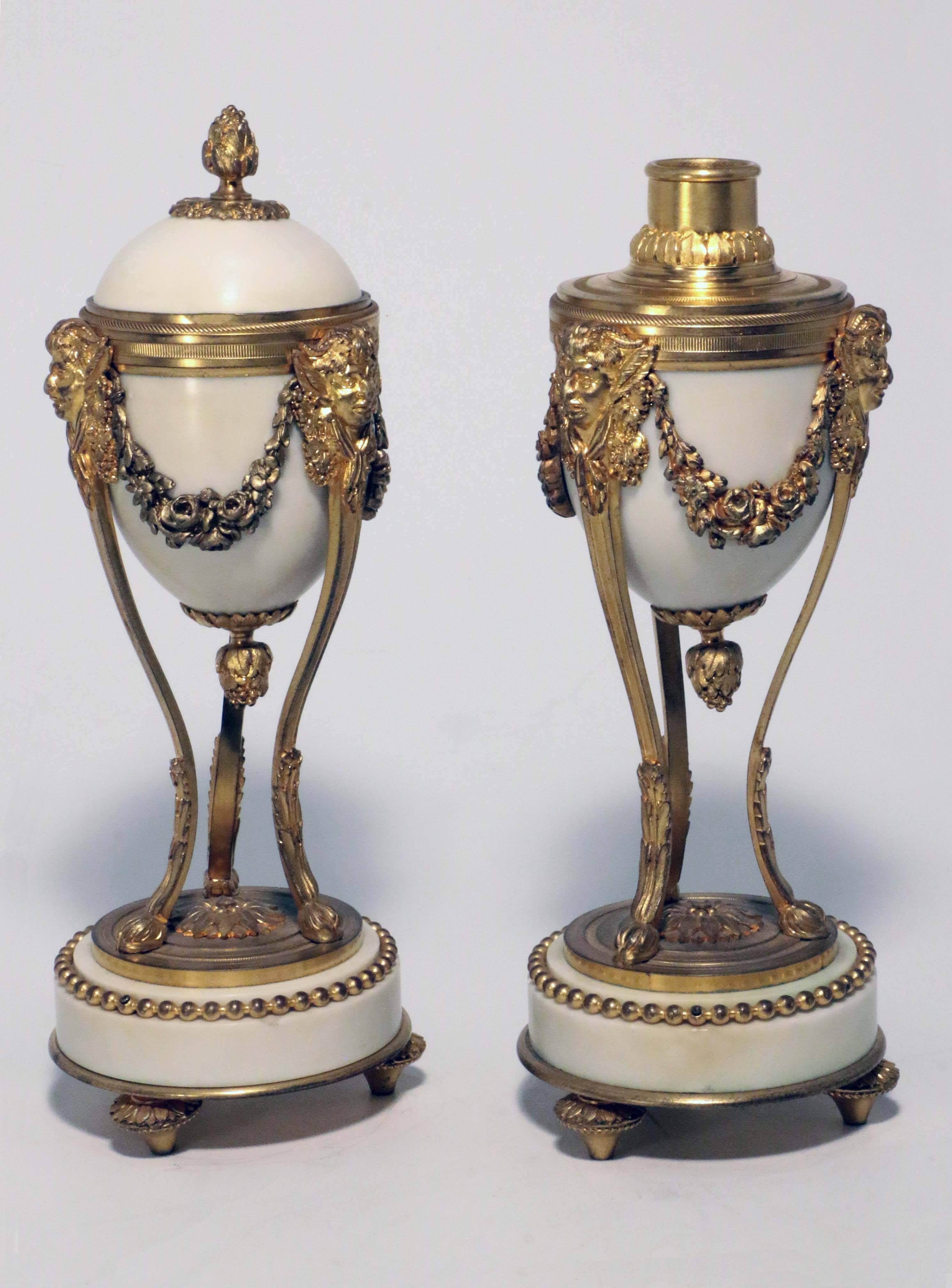 Each egg-shaped marble body mounted in gilt bronze and on a stand formed as masks of the young Silenus linked by garlands, and raised on three slender supports on beaded marble platform base and toupie feet. The domed cover reset upside down reveals