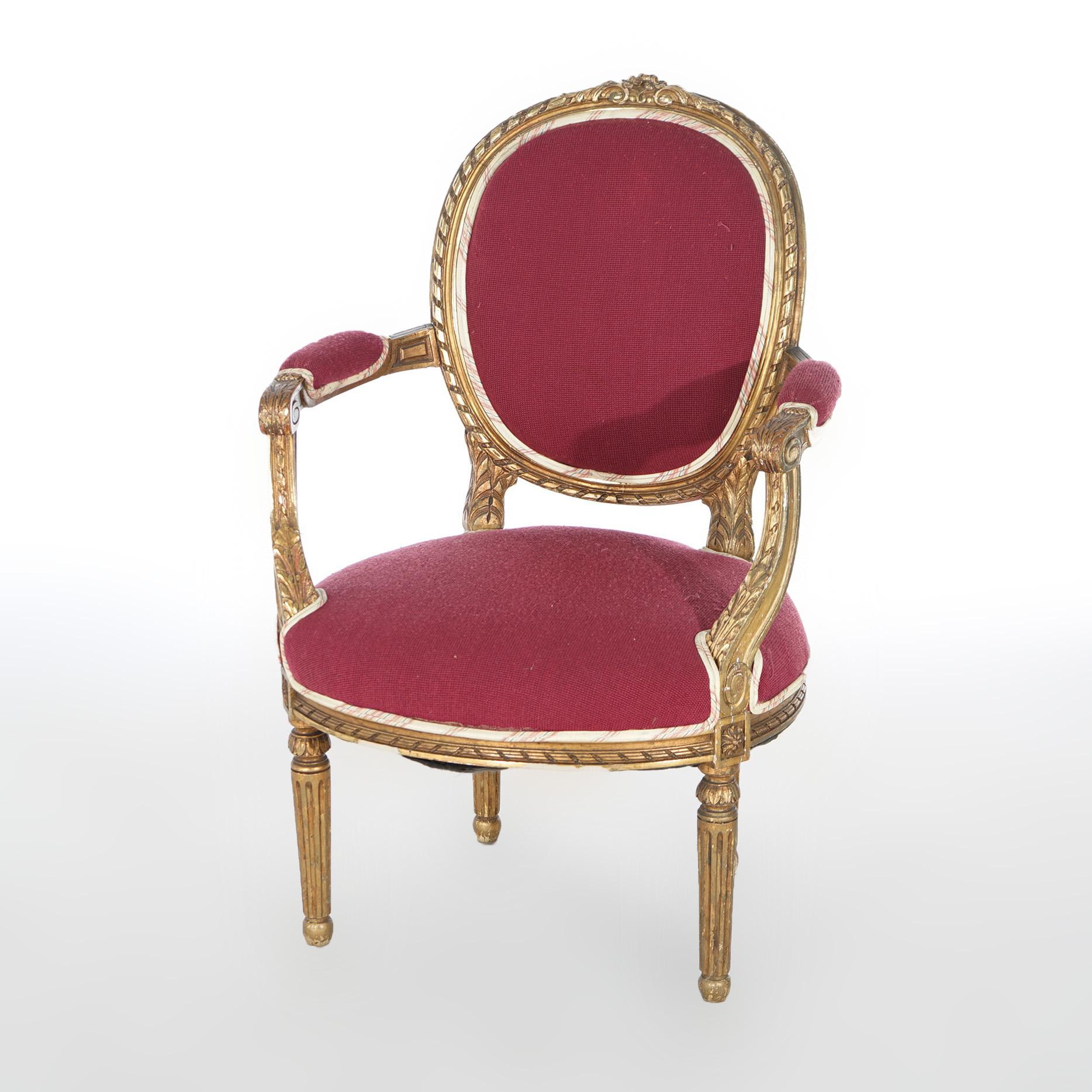An antique pair of French Louis XVI style arm chairs offer giltwood construction with upholstered seats and backs, covered scroll form arms and raised on fluted tapered legs, c1920

Measures- 37.75''H x 25.75''W x 24''D; SH 17