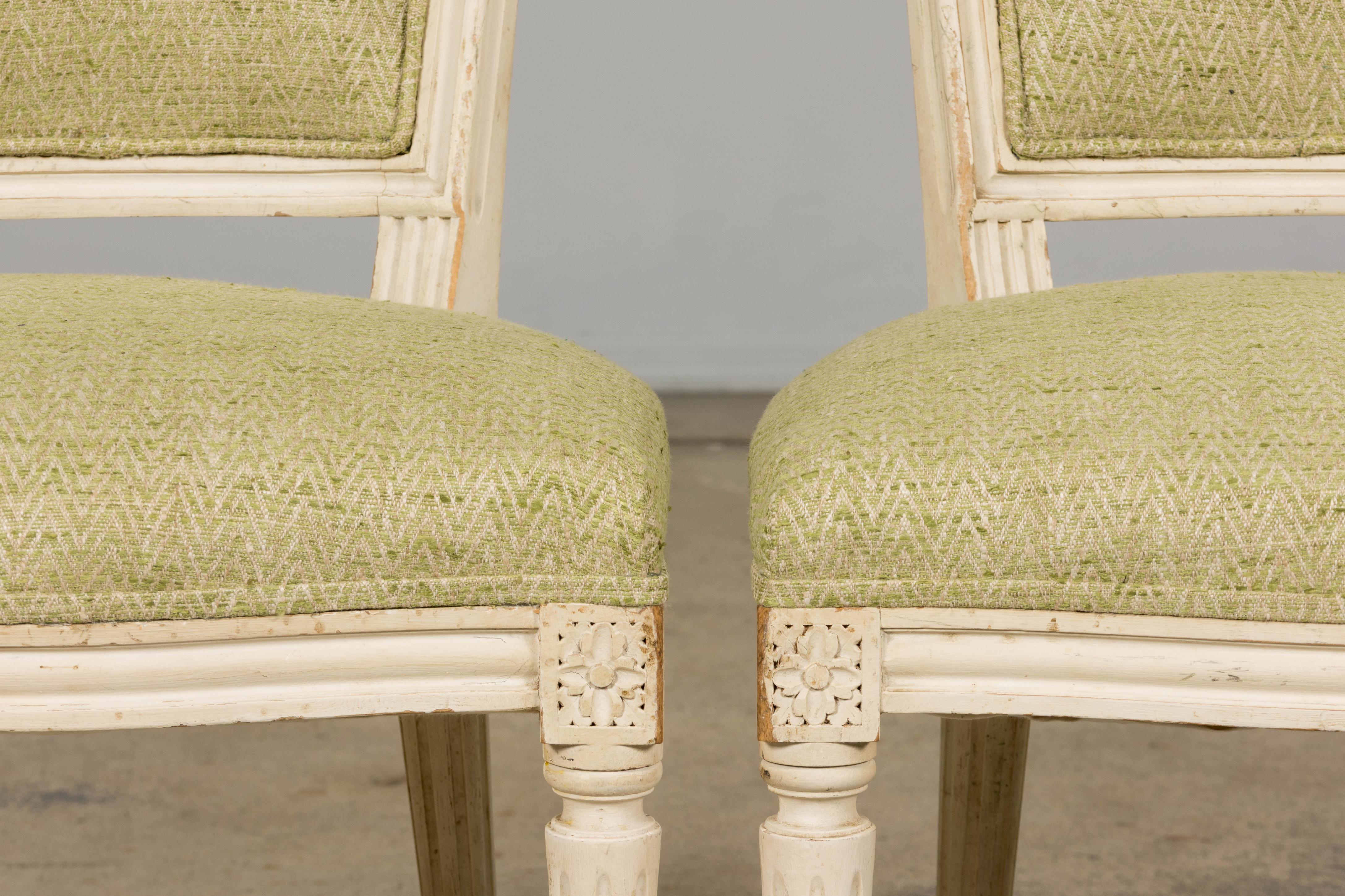 Exquisita pareja de antiguas sillas de acento francesas restauradas de estilo Marie Antoinette-Louis XVI, procedentes de Provenza. Cada silla presenta un respaldo en forma de escudo finamente tallado a mano, acabado en un cremoso blanco antiguo con