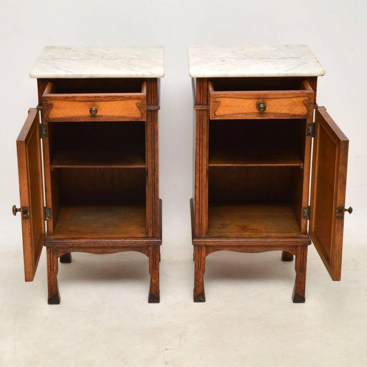 Pair of antique French marble-top bedside cabinet in oak with walnut inset panels. They are in good original condition & date from around the 1890 period. The marble tops are in good condition & original to the cabinets. The brass handles look