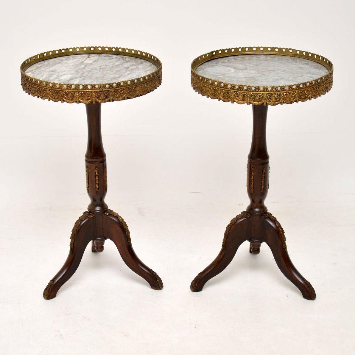 Pair of antique French style marble top wine tables in good original condition. They are mahogany with matching marble tops, surrounded by gilt metal galleries, sitting on turned mahogany bases with tripod legs. There are various gilt bronze mounts