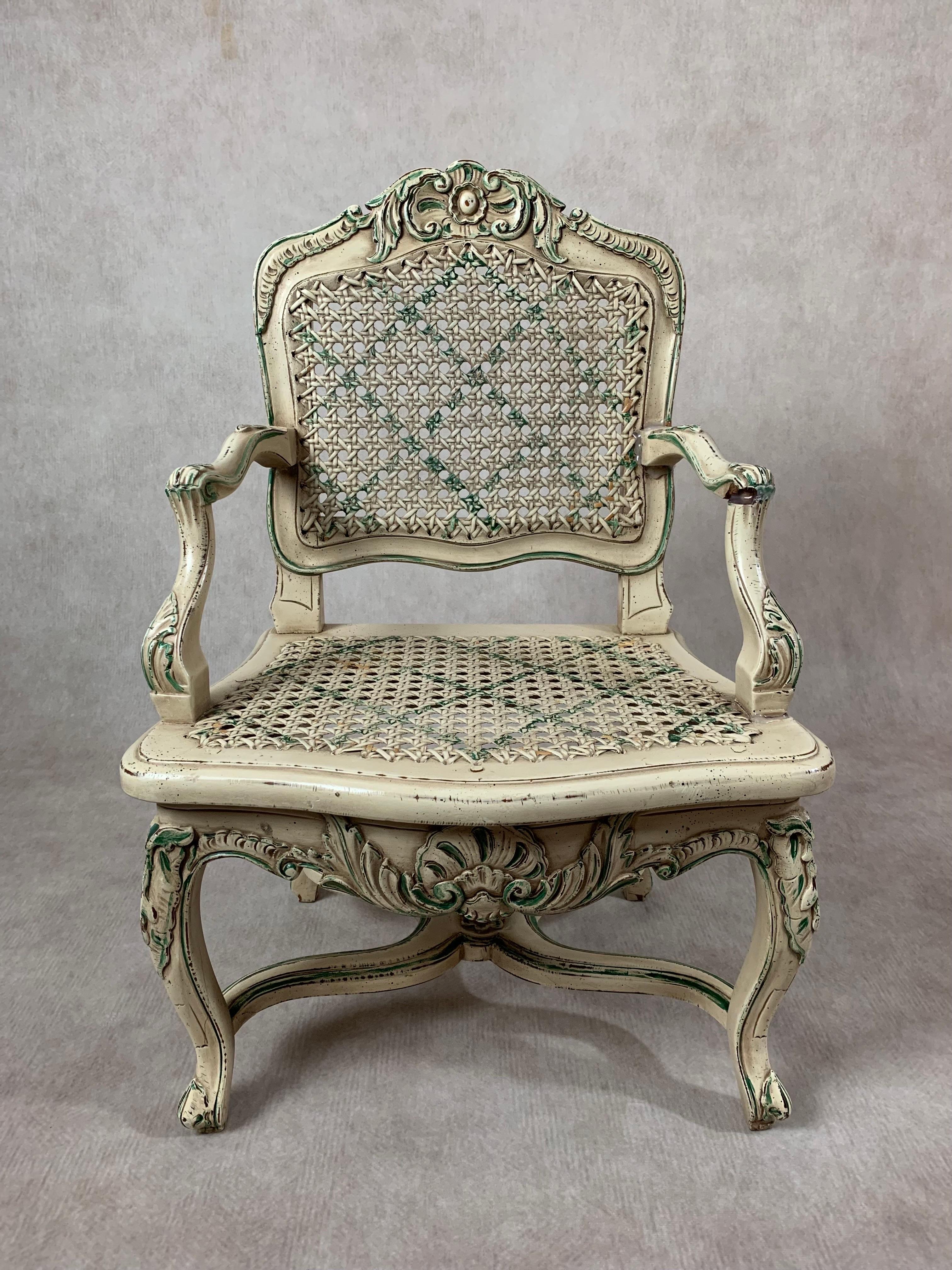 A darling pair of miniature Louis XVI style caned arm chairs featuring ornately carved and cast scrollwork with hand-painted details, cabriole legs, caned back and seat. One chair displays green accents and the other salmon pink. 

Perfect for