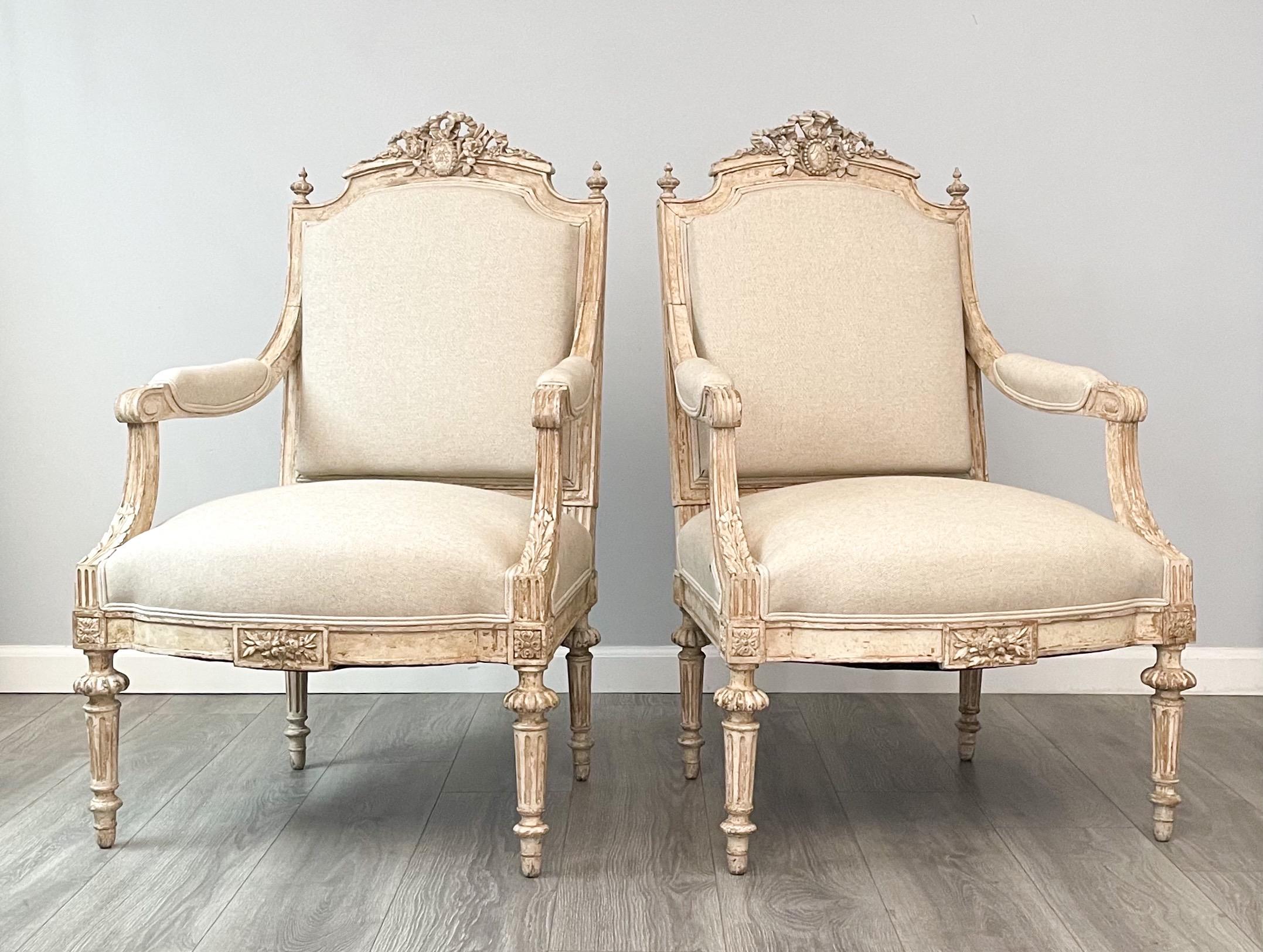 Fine pair of 1920s French arm chairs in the neoclassical style.

The chairs feature beautifully carved wood frames, a naturally distressed paint finish and new cotton linen canvas upholstery.

A very elegant pair of chairs which can be