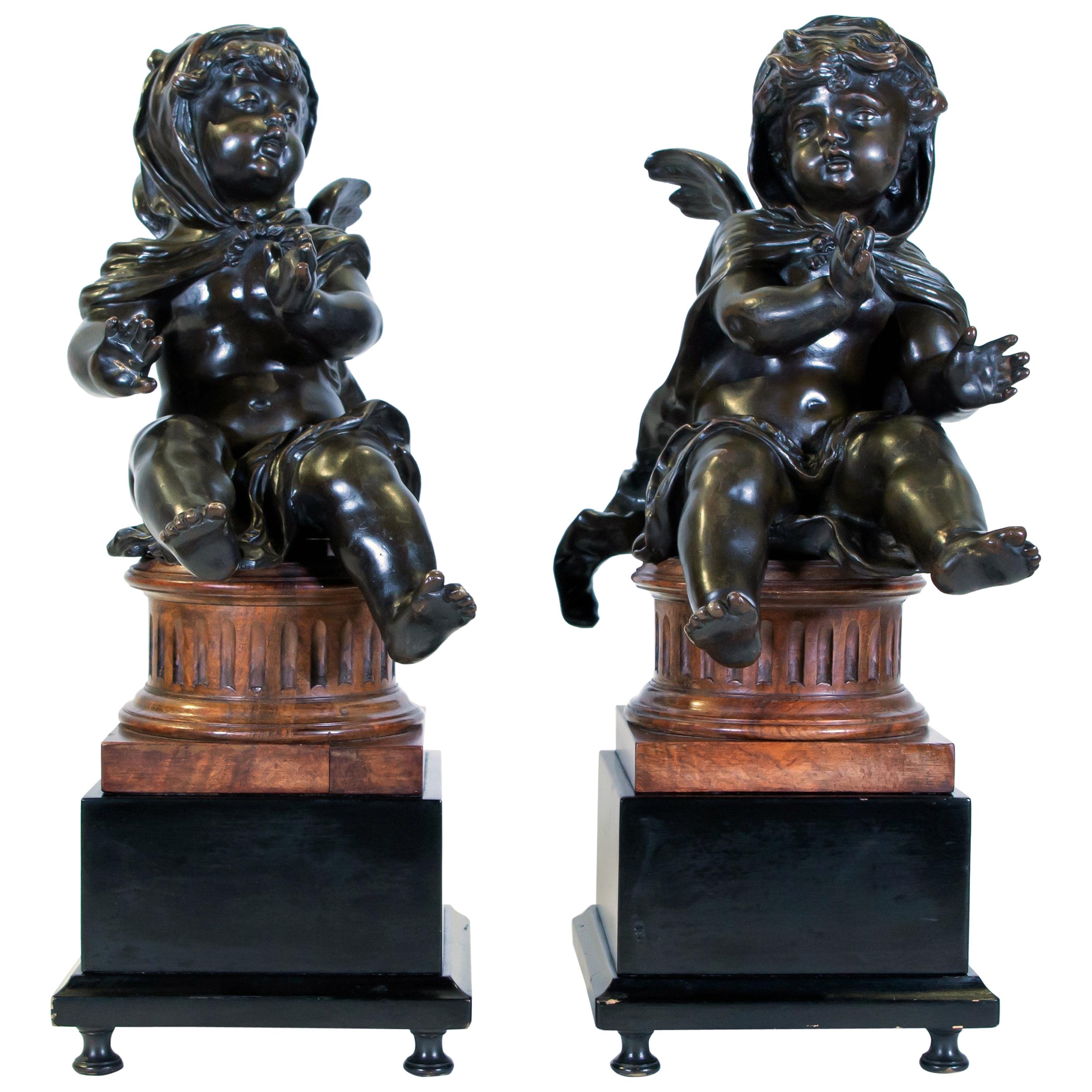 Paar antike französische geflügelte Putten aus patinierter Bronze, sitzend auf kannelierten Sockeln im Angebot